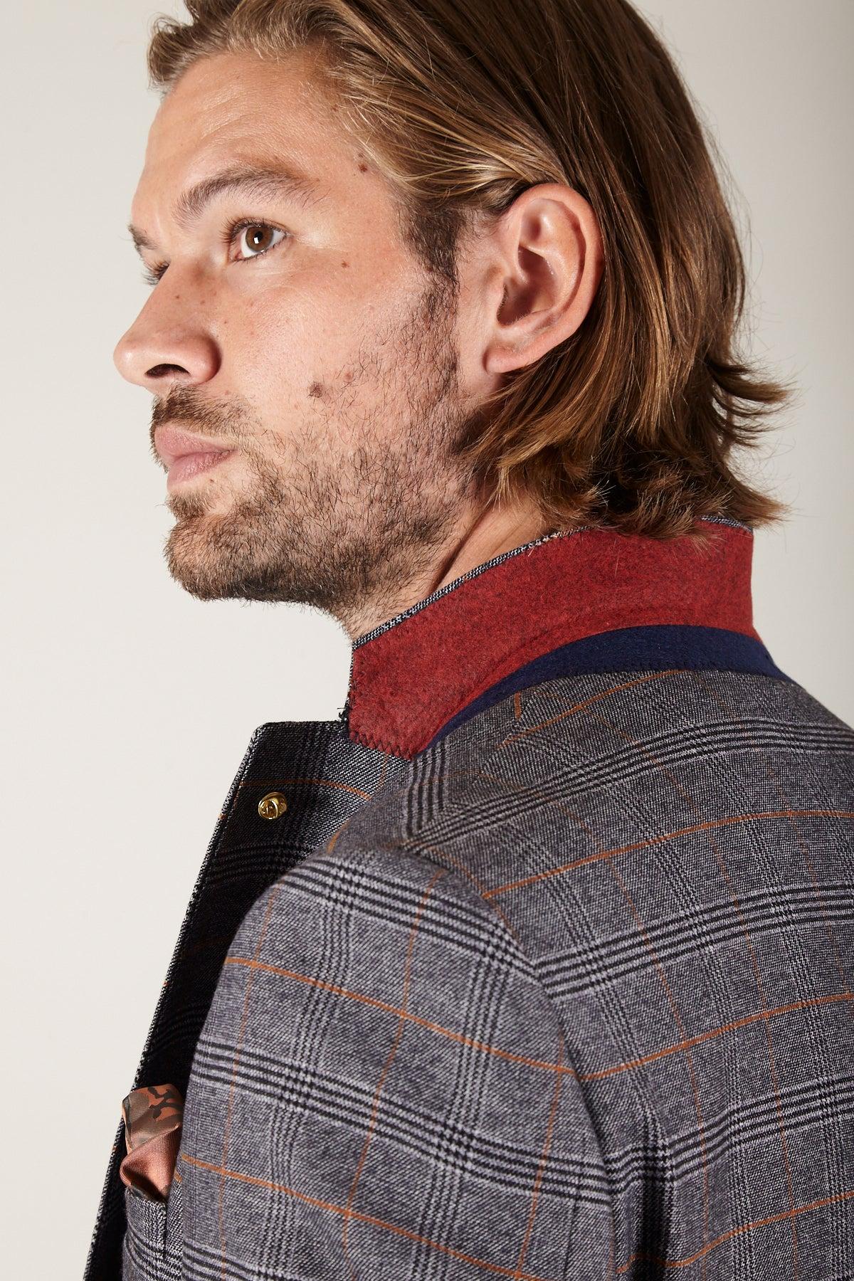 A man with light brown hair and a short beard wears the marcdarcy JENSON Grey Check Suit with KELVIN Tan Waistcoat, looking off to the side against a neutral background.