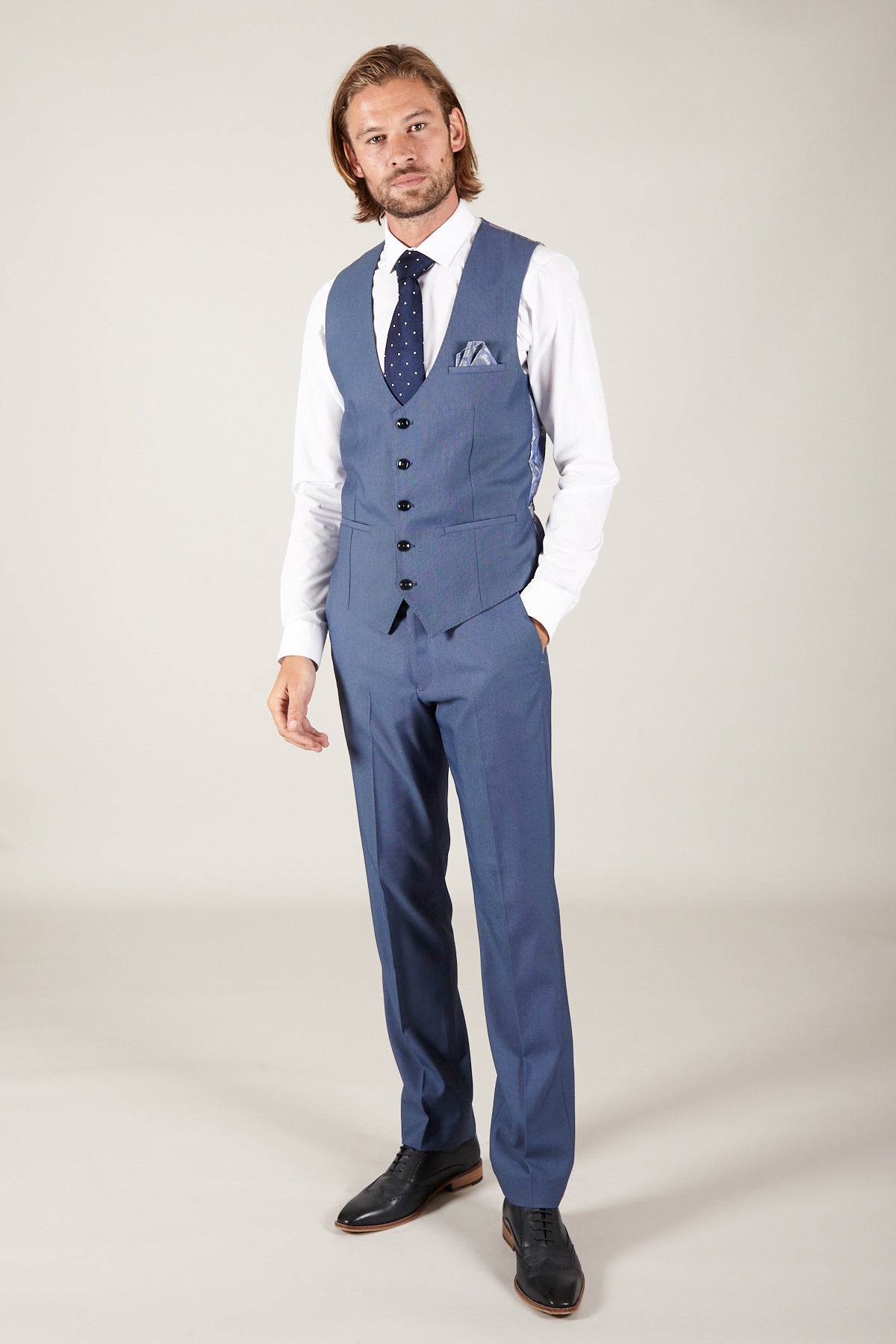 A man wears the Marc Darcy DANNY - Sky Single Breasted Waistcoat with a white shirt, blue polka dot tie, and pocket square, standing against a plain background to showcase smart workwear style.