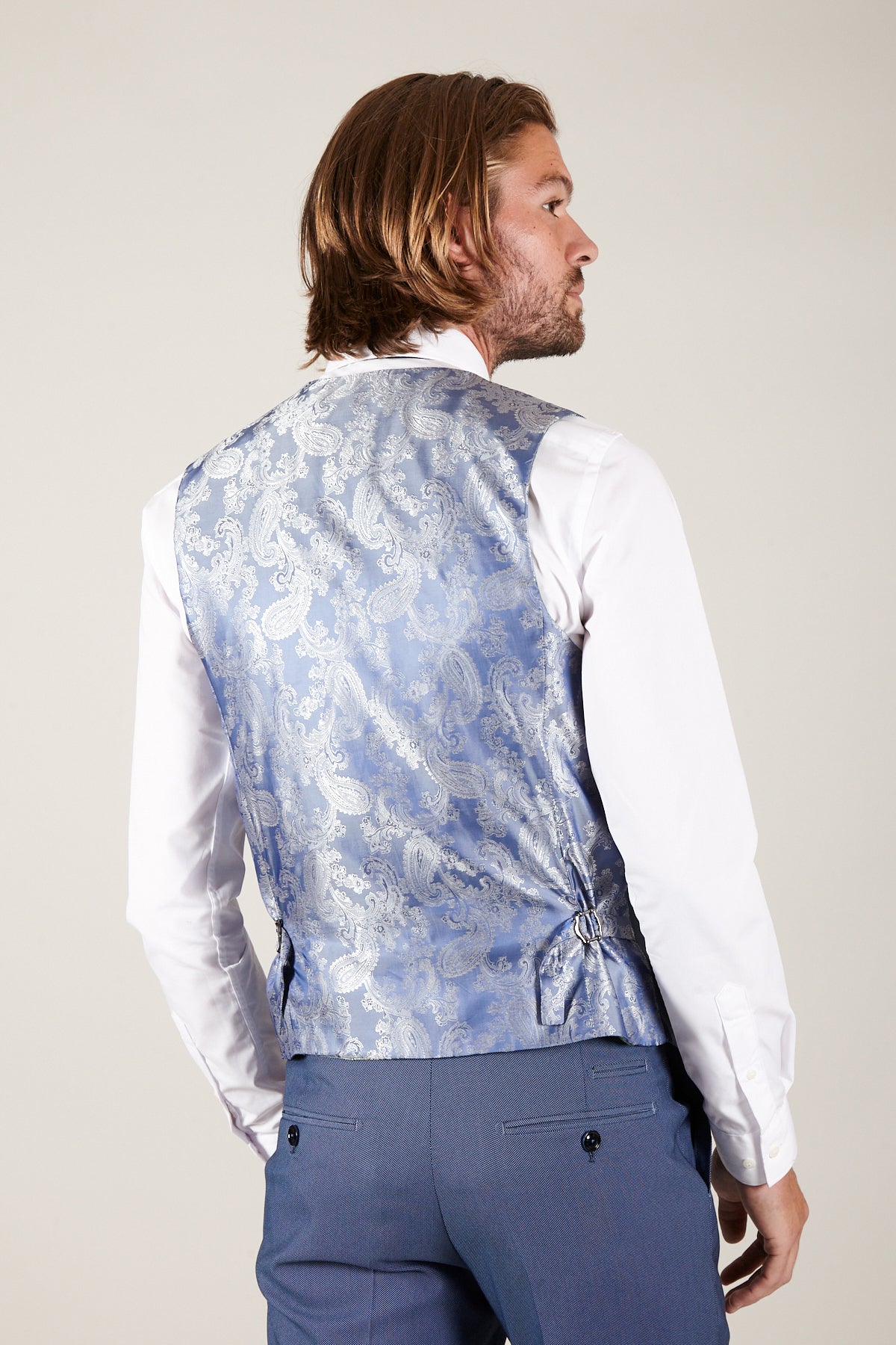 Back view of a man wearing a slim fit white dress shirt, blue dress pants, and the Marc Darcy DANNY - Sky Single Breasted Waistcoat.
