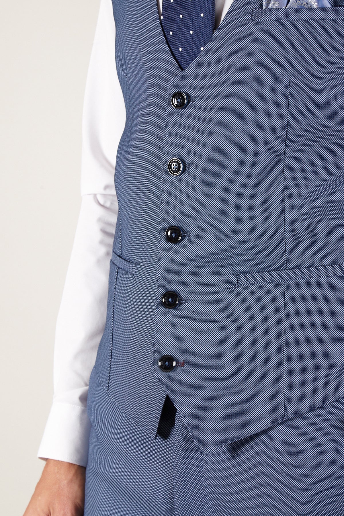 A person wearing the Marc Darcy DANNY - Sky Single Breasted Waistcoat with matching pants, a white shirt, and a dark blue polka dot tie—a workwear classic. Only the torso plus part of the left arm and hand are shown.
