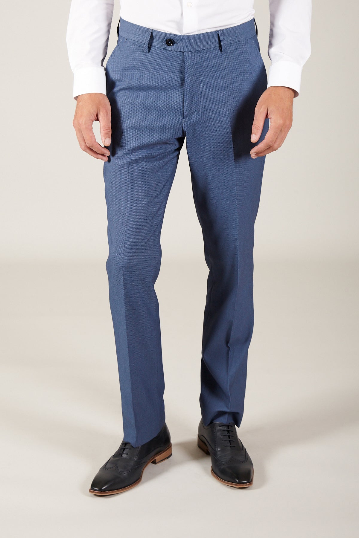 A person wears Marc Darcy DANNY - Sky Tailored Trousers, paired with a white dress shirt and black dress shoes, standing against a plain light background. Only the lower half of the body is visible.