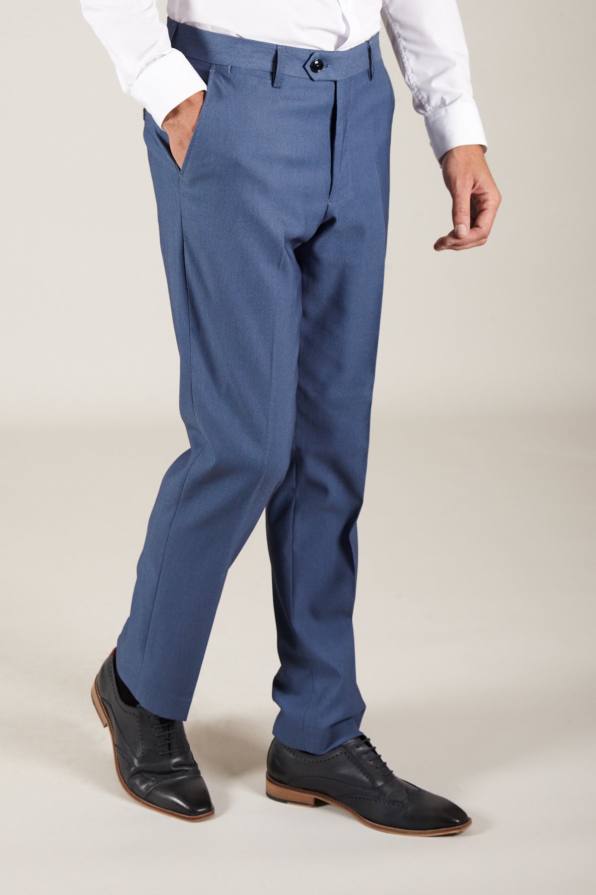 A person dressed in a white shirt, Marc Darcy DANNY - Sky Tailored Trousers, and black leather dress shoes stands with hands in pockets against a plain background.