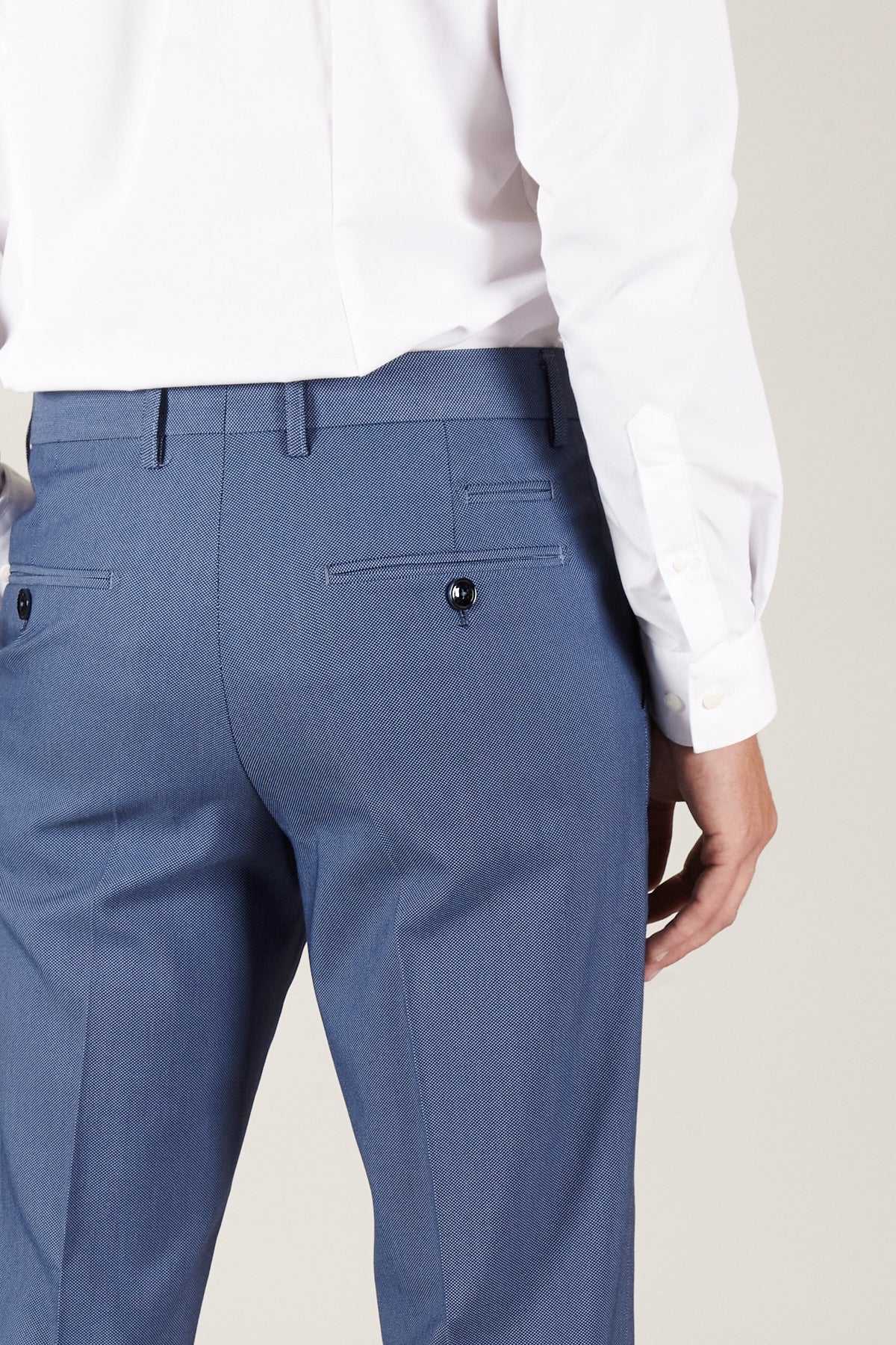 A person is shown from the back wearing a white dress shirt and Marc Darcy DANNY - Sky Tailored Trousers, featuring belt loops and buttoned back pockets. Their right arm is slightly bent by their side.