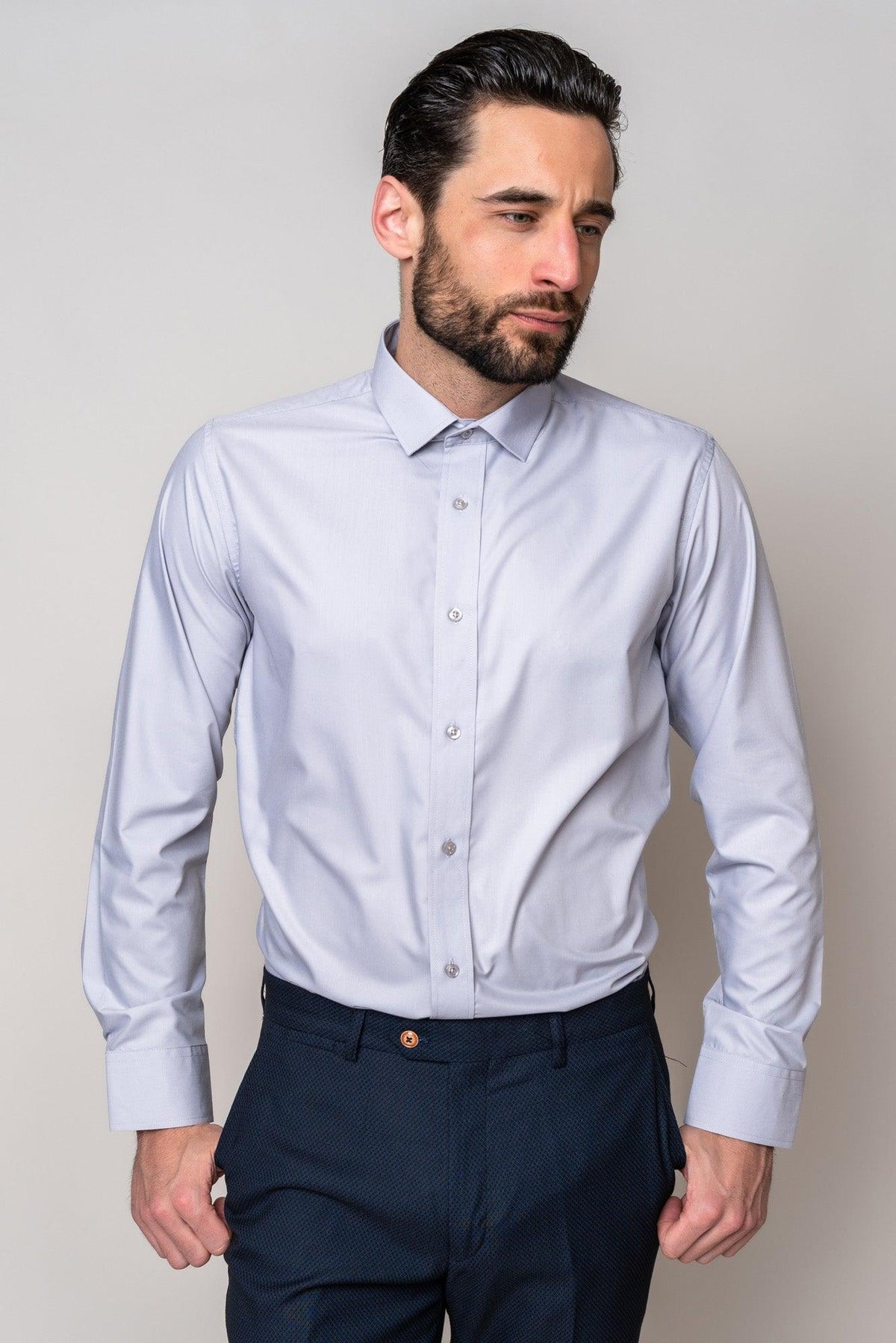 A man with dark hair and a beard wears the Marc Darcy CARTER Silver Long Sleeve Shirt and dark trousers, standing against a plain light background with his hands at his sides, looking slightly to the left.
