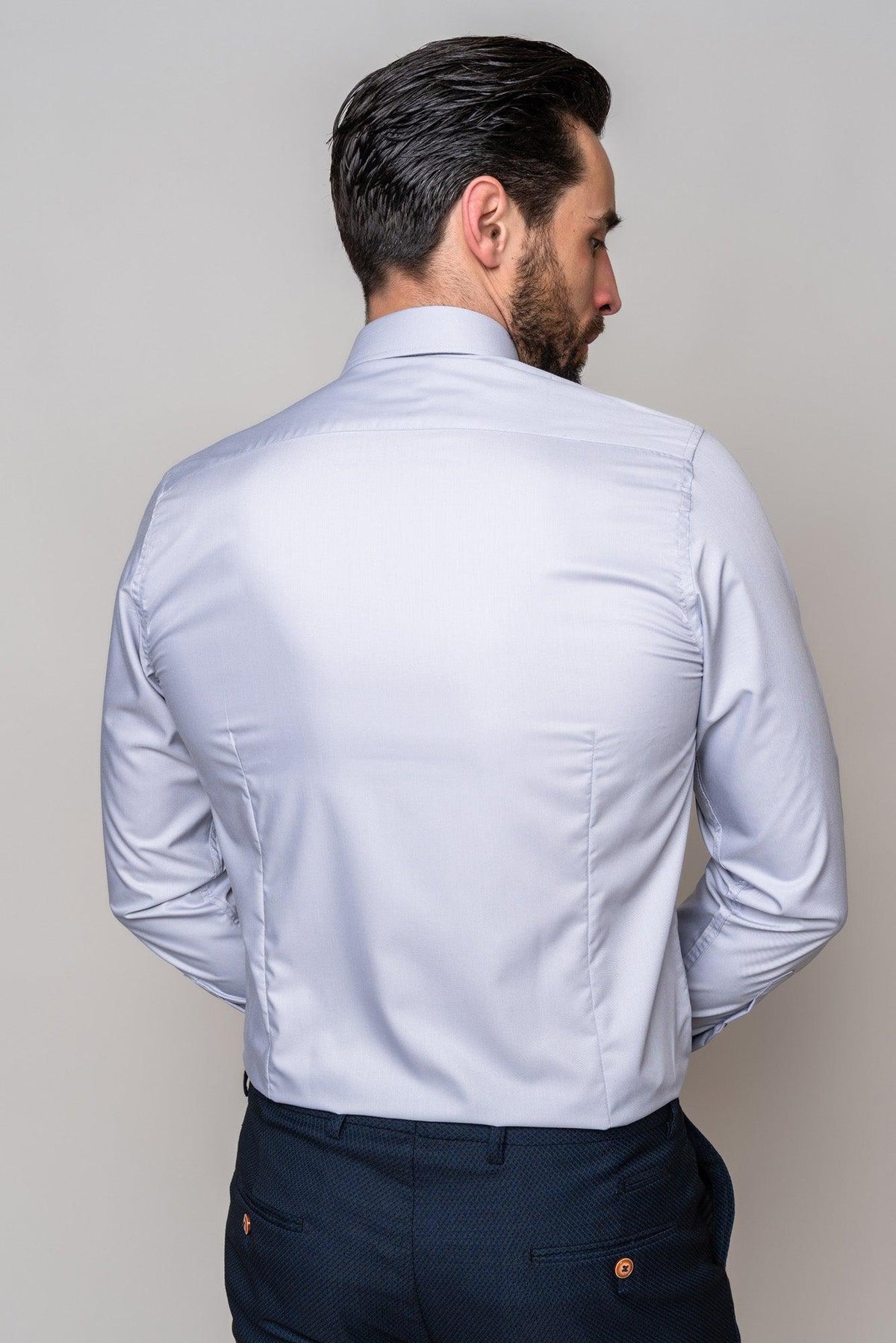 A man with dark hair is seen from the back wearing a Marc Darcy CARTER - Silver Long Sleeve Shirt and dark trousers, standing against a plain light background.