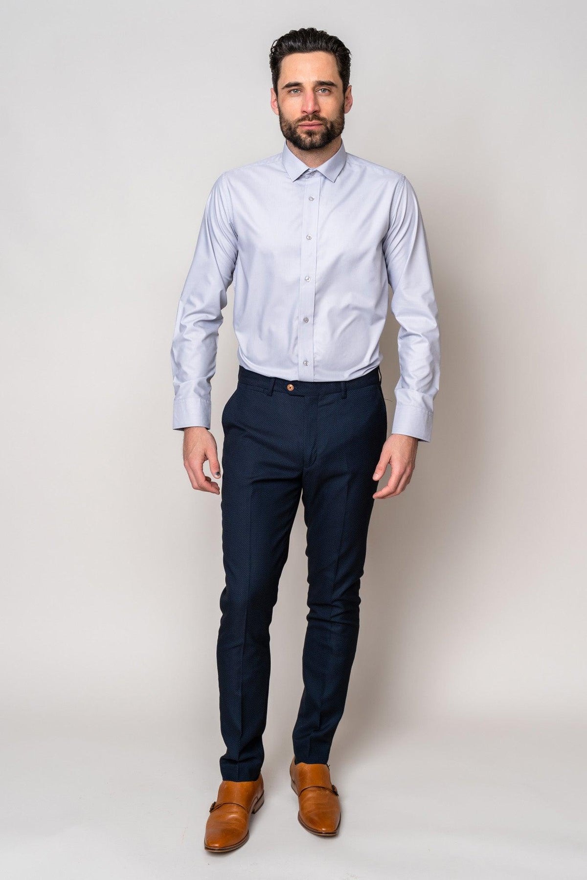 A man with dark hair and a beard stands against a light background, wearing the Marc Darcy CARTER Silver Long Sleeve Shirt, navy dress pants, and brown dress shoes, looking forward with a neutral expression.