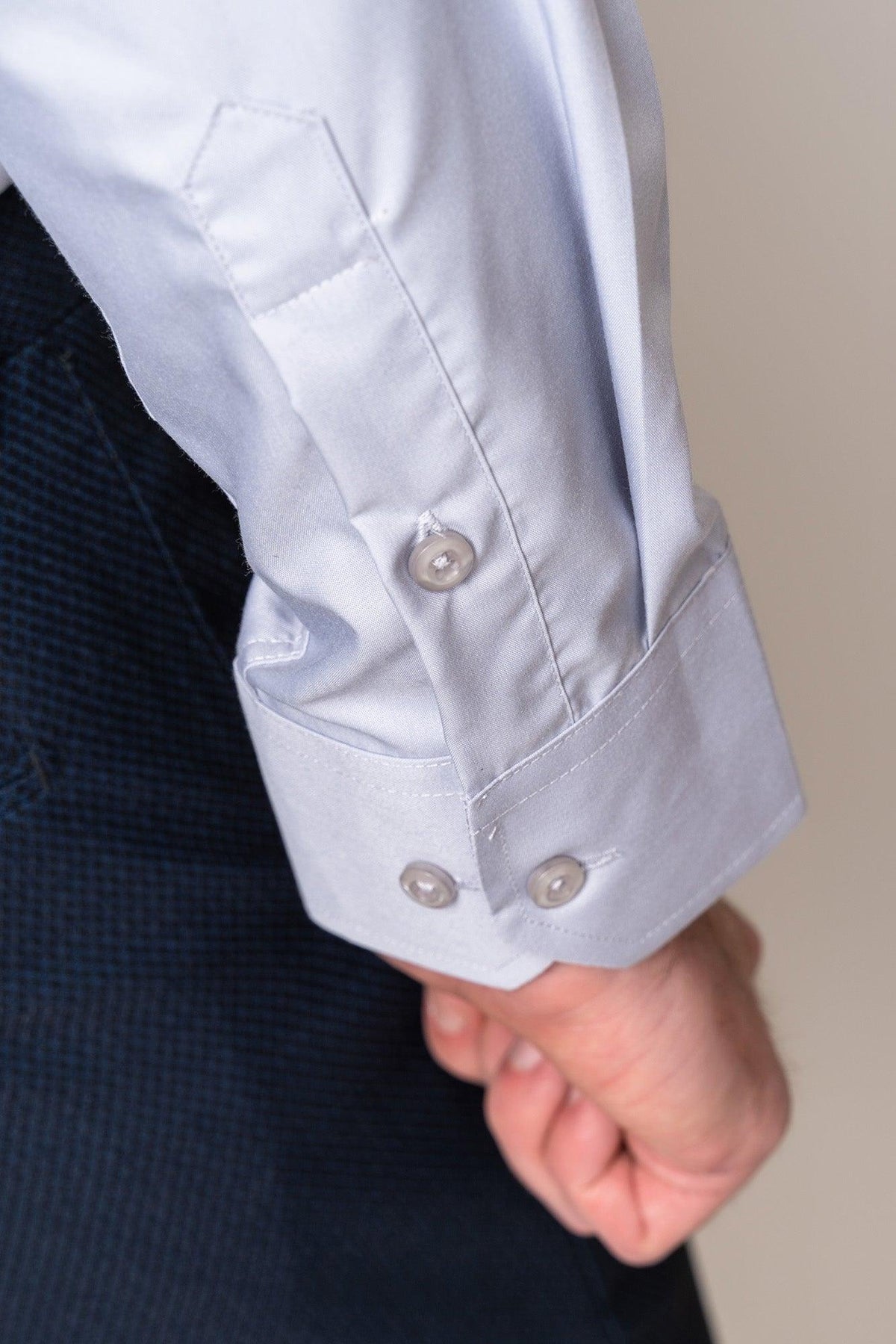 Close-up of a person’s arm wearing the Marc Darcy CARTER - Silver Long Sleeve Shirt with two white cuff buttons, paired with dark blue textured pants. The person’s relaxed hand is partially visible.