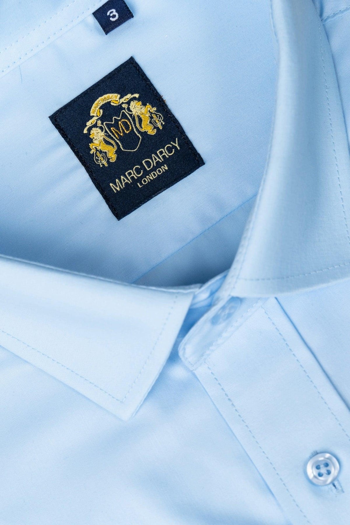 The CARTER Sky Long Sleeve Shirt by Marc Darcy features a classic fit, size 3 tag, and a gold embroidered crest on the spread collar.
