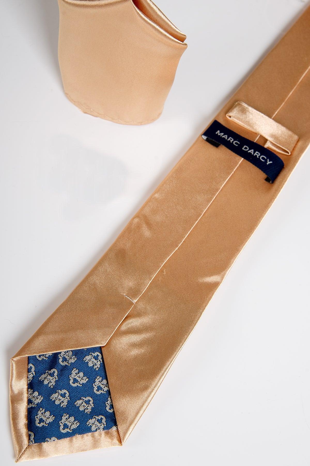 The STANLEY Satin Tie and Pocket Square Set in Gold by Accessory features a gold satin tie with blue floral lining and matching pocket square, both elegantly displayed on white. The MARC DARCY label accents the back of the tie.