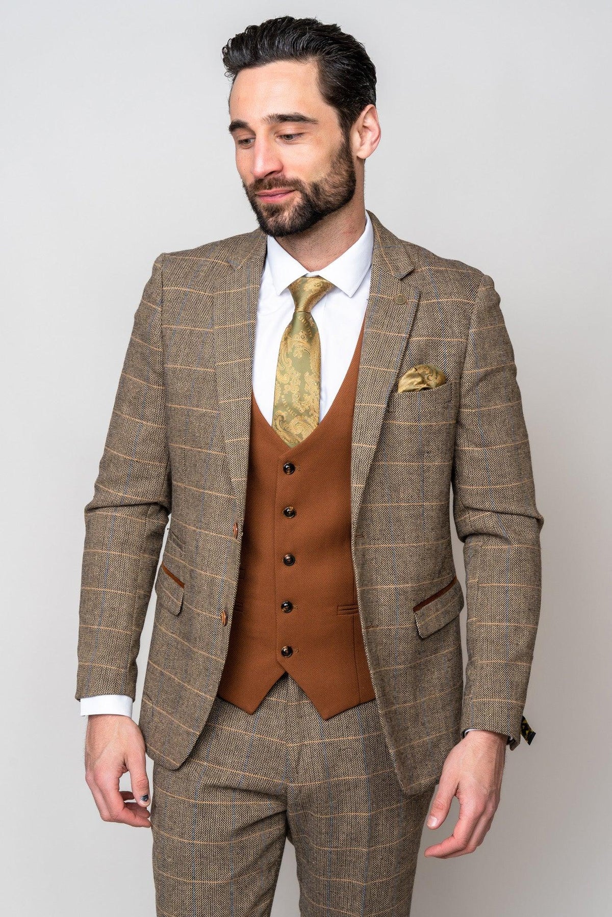 A man wears the marcdarcy TED Tan Tweed Check Suit with Kelvin Tan Waistcoat—an ideal choice for a country barn wedding—styled with a gold paisley tie and pocket square.