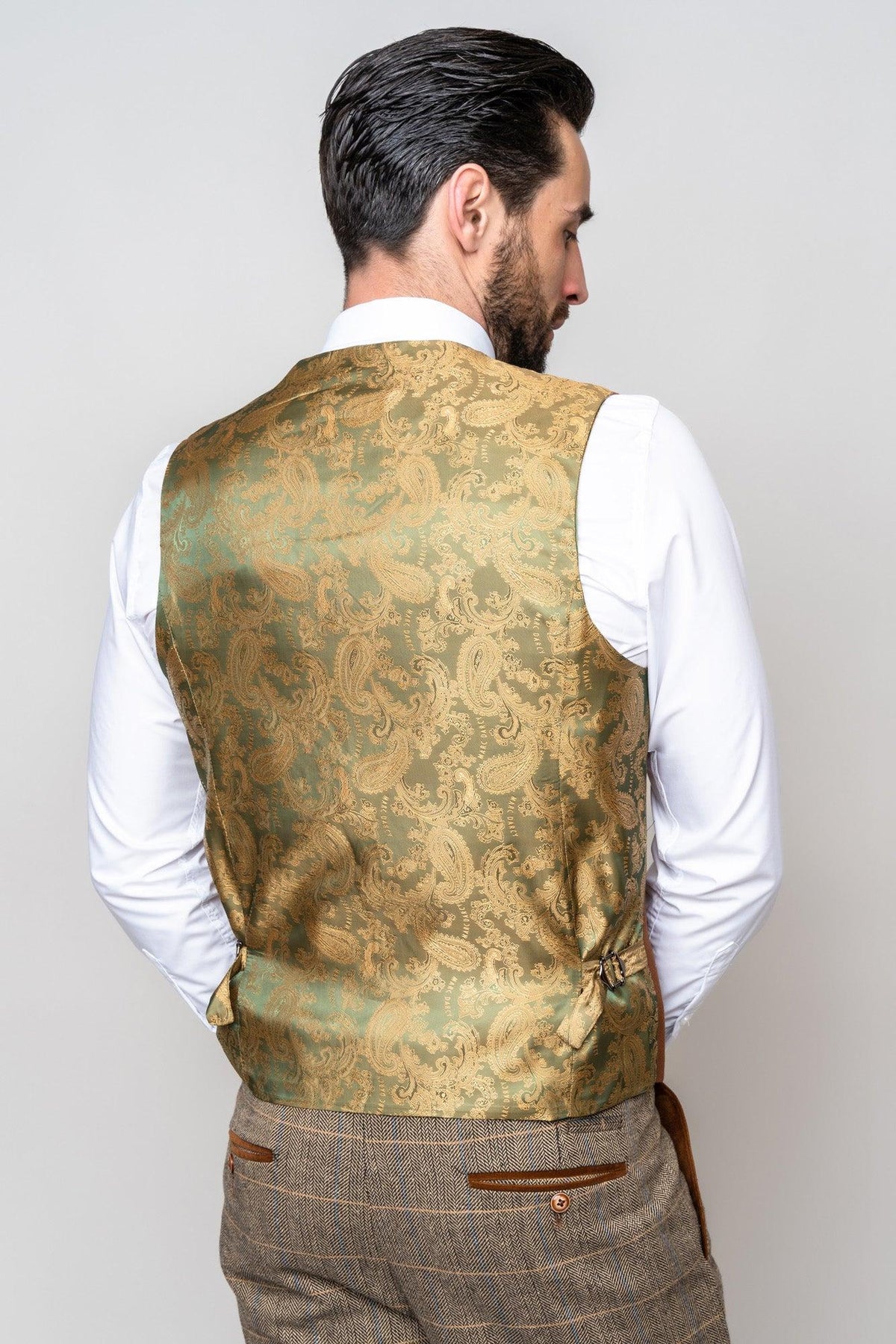 A man with dark hair, seen from behind, wears the marcdarcy TED Tan Tweed Check Suit with Kelvin Tan Waistcoat—ideal for a country barn wedding—standing against a light grey background.