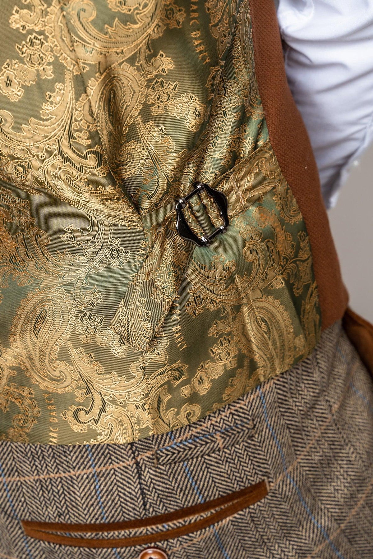 Close-up of the back of the marcdarcy TED - Tan Tweed Check Suit with Kelvin Tan Waistcoat, showing a green and gold paisley adjustable buckle, styled with a white shirt and buttoned brown tweed trousers—ideal for country barn weddings.