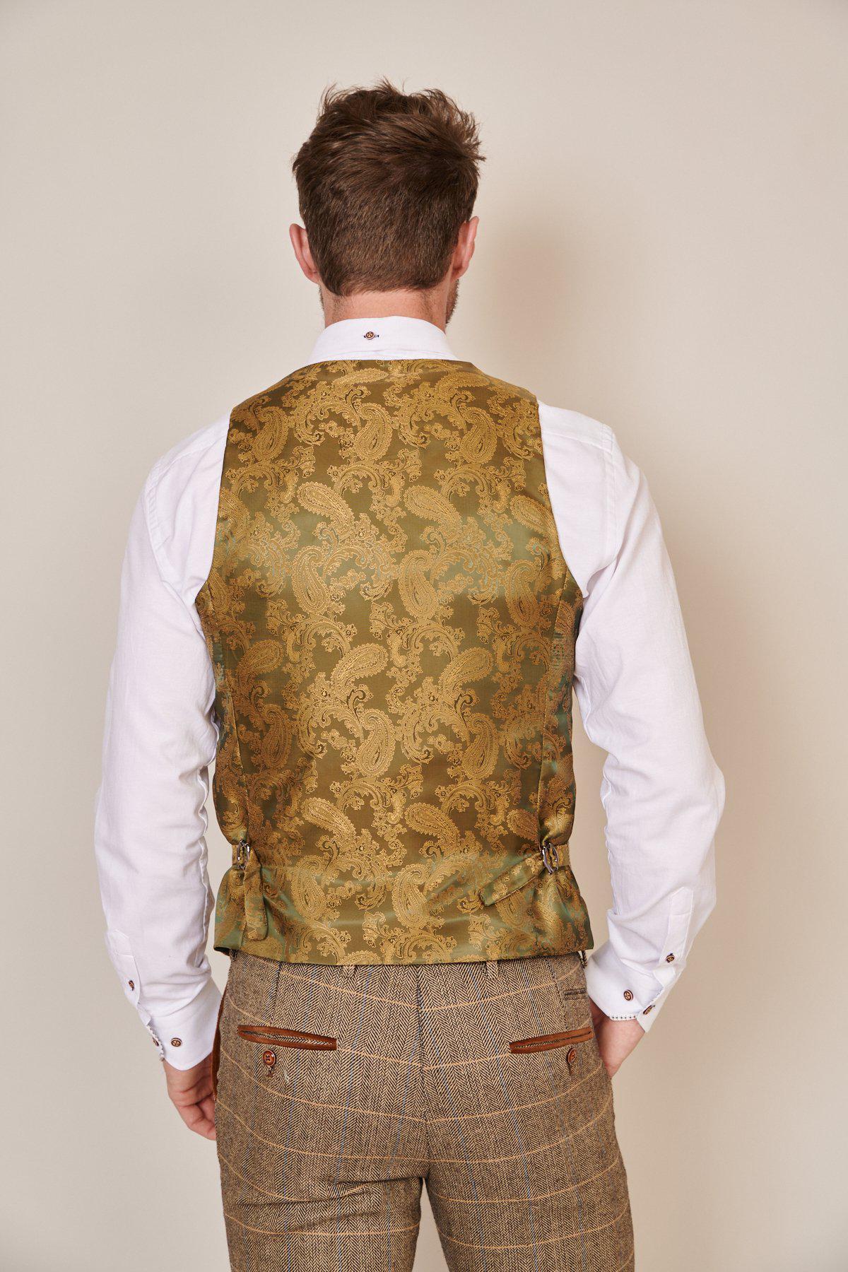 Peter Reid and Sam Allardyce wear marcdarcy’s Max Navy Suit with Ted Waistcoat. The look features a gold and green paisley waistcoat, white shirt, brown plaid trousers, camouflage pocket square, and a plain light background.