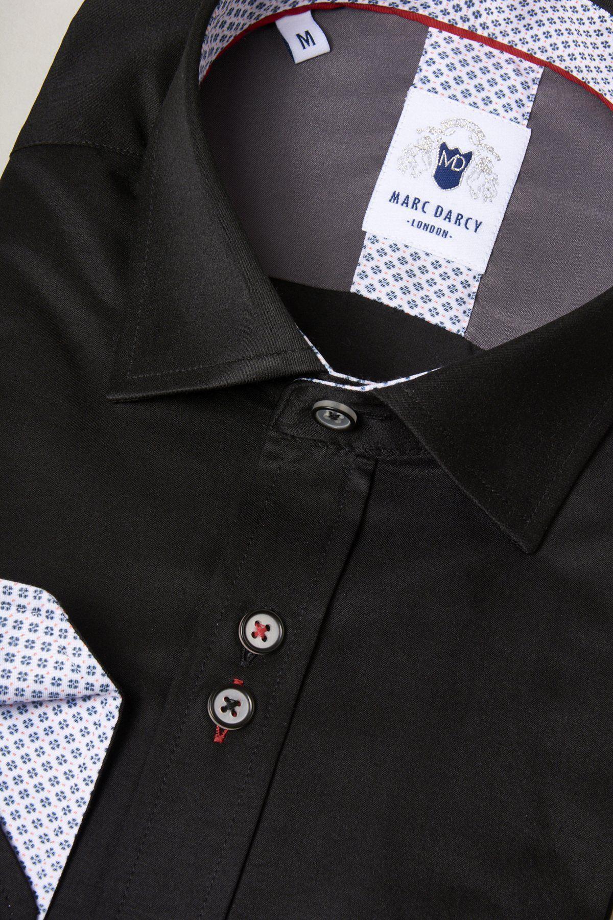 A close-up of the Marc Darcy ALFIE black long sleeve shirt, featuring a spread collar, contrasting patterned white fabric on the pocket and collar lining, dark buttons with white stitching, and a branded label inside the collar.