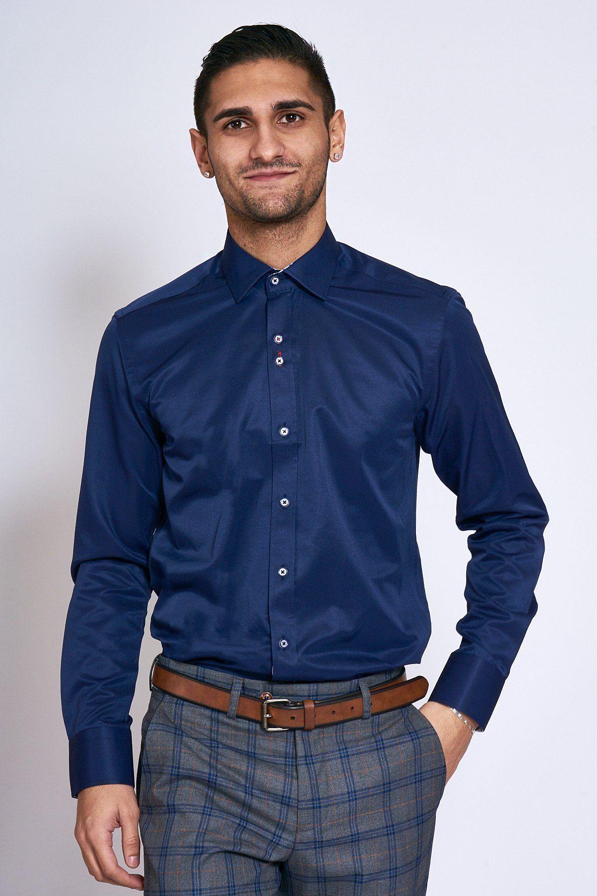 A man wearing the Marc Darcy ALFIE Navy Long Sleeve Shirt paired with grey plaid pants, a brown belt, and a silver bracelet.