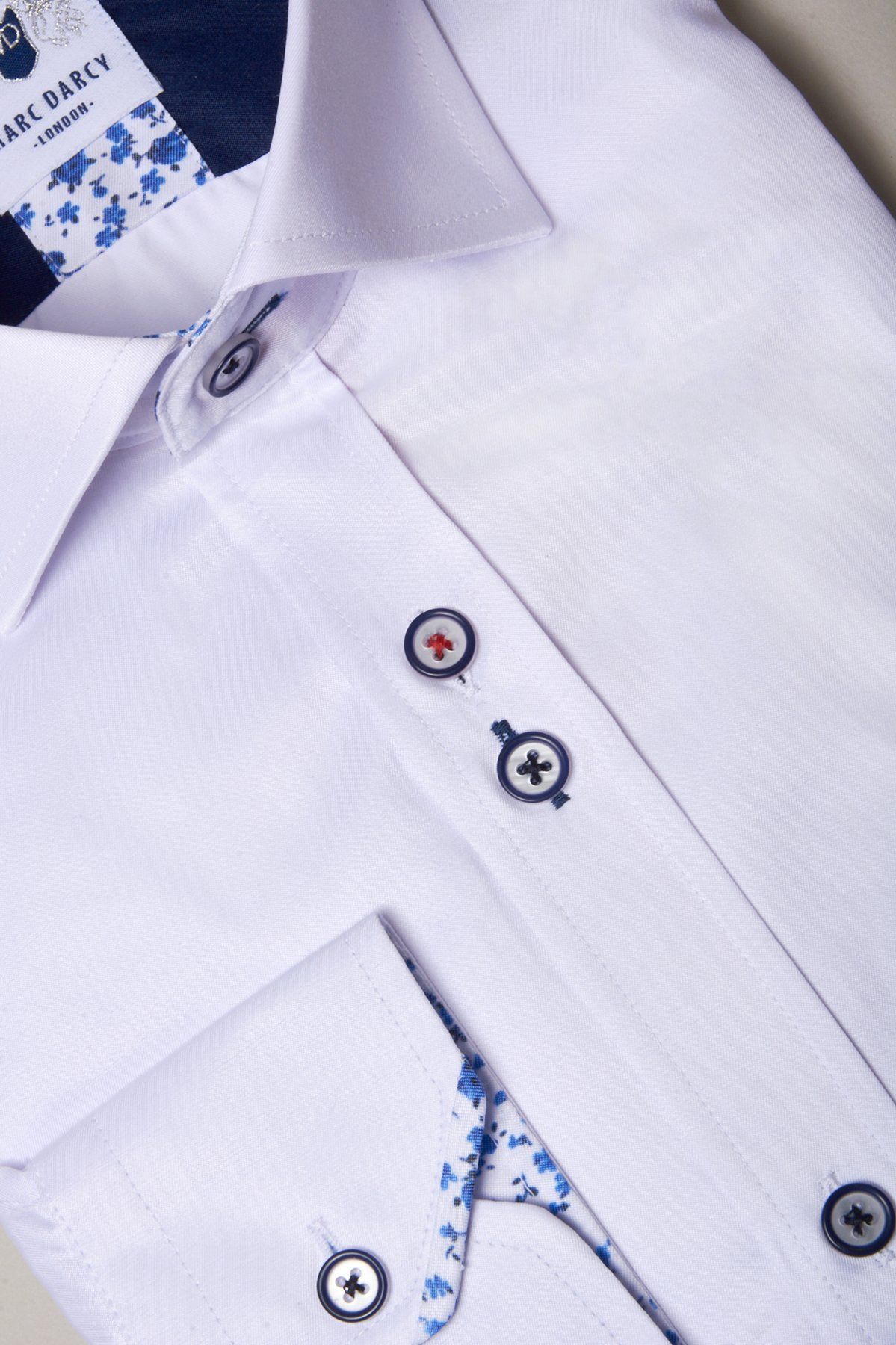The ALFIE White Long Sleeve Shirt by Marc Darcy features contrasting blue and red buttons, blue floral trim inside the collar and placket, and a visible Marc Darcy London label.