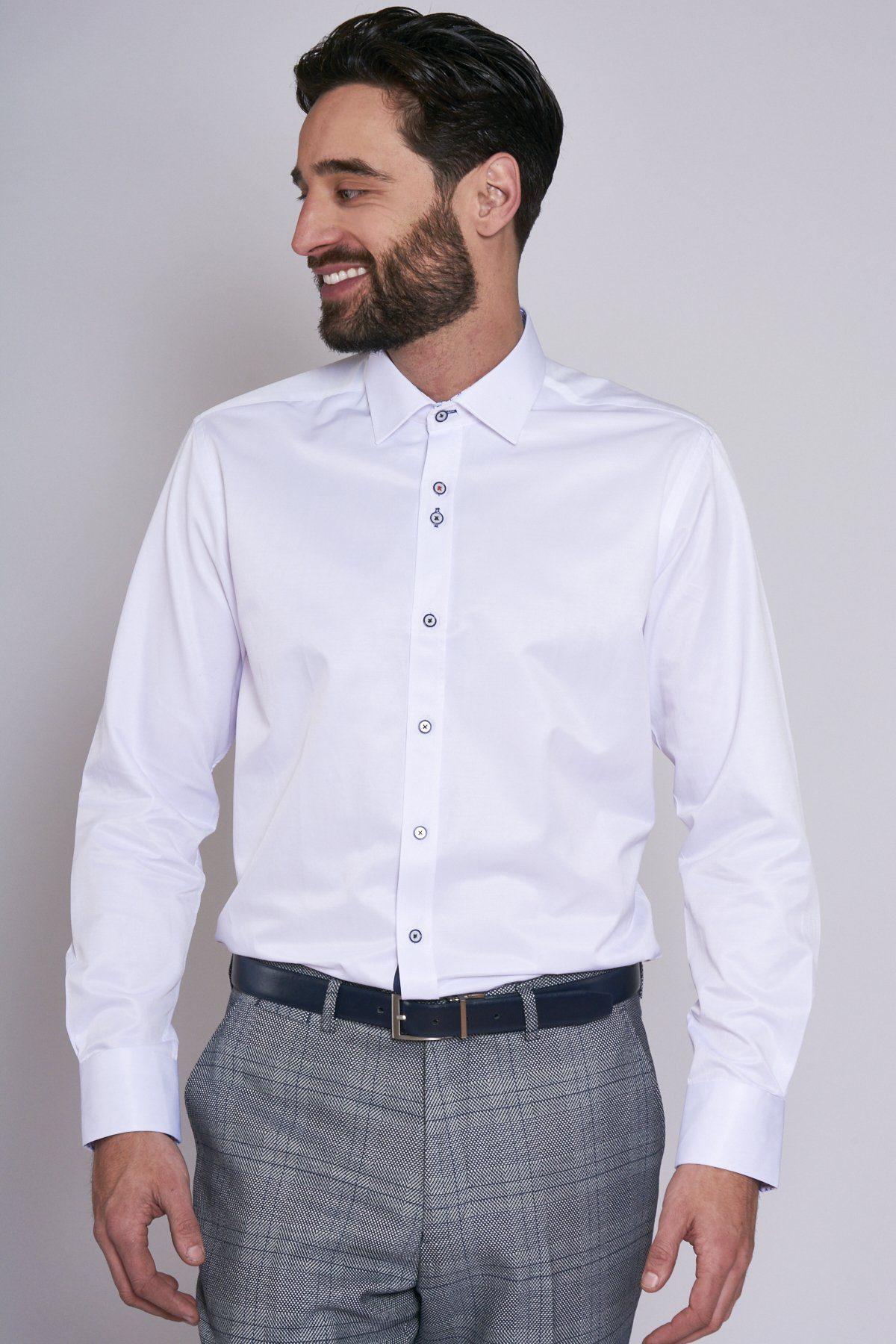 A man with dark hair and a beard smiles and looks left, wearing the ALFIE White Long Sleeve Shirt by Marc Darcy, grey plaid trousers, and a black belt against a plain light background.