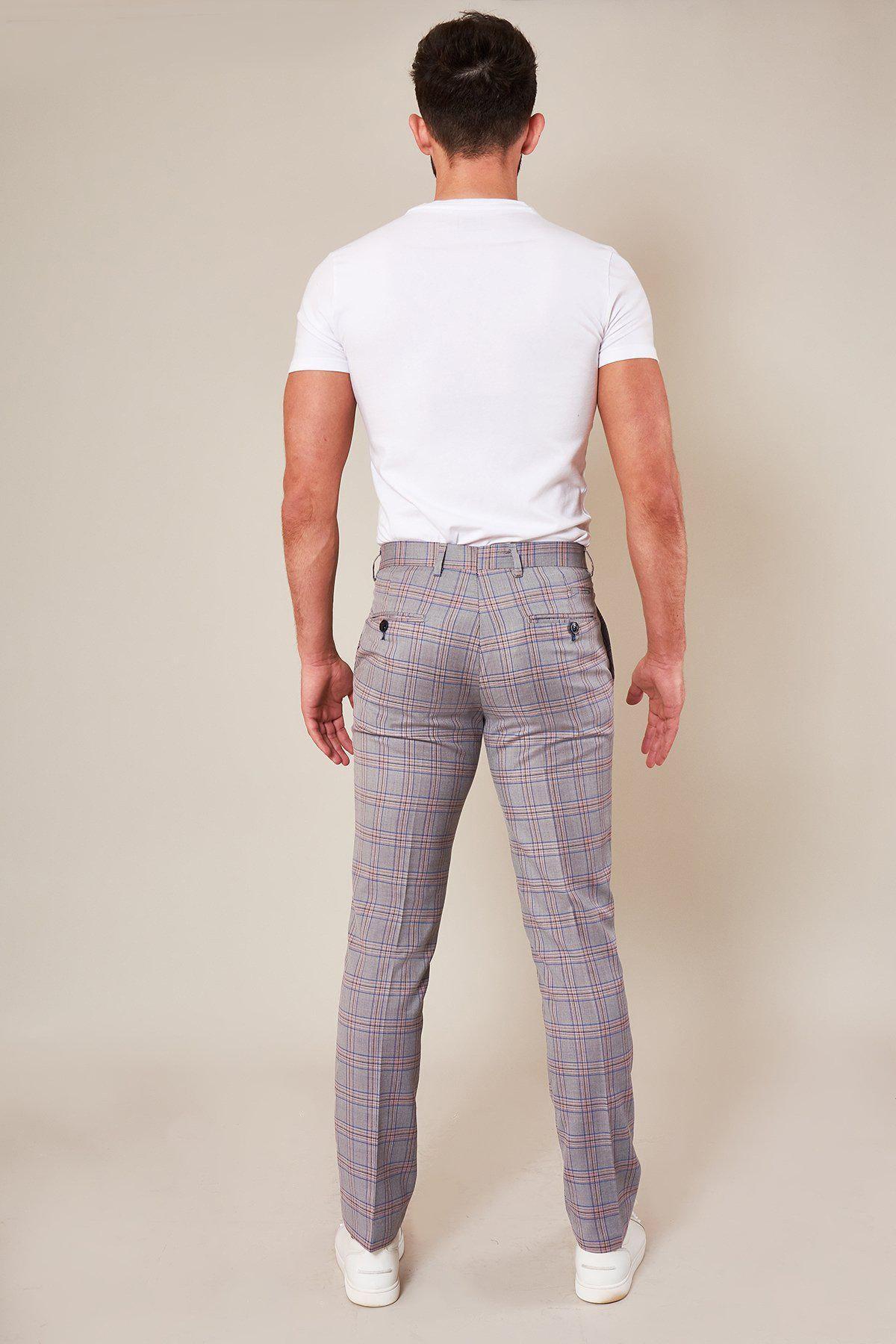 A man faces away from the camera, wearing a fitted white t-shirt, white sneakers, and Marc Darcys ALVIN - Grey Pink Check Trousers, set against a plain light background.