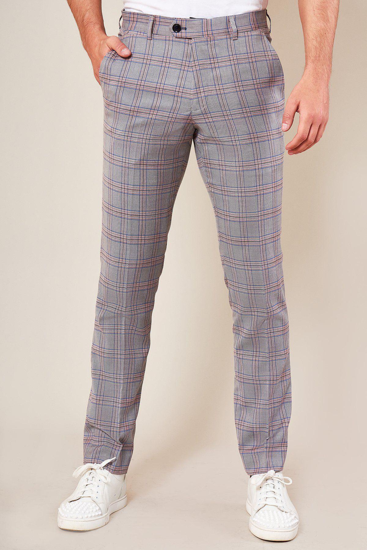 A person stands hands in pockets against a plain background, wearing Marc Darcy's ALVIN Grey Pink Check Trousers, crafted from lightweight fabric, paired with a white shirt and white sneakers.