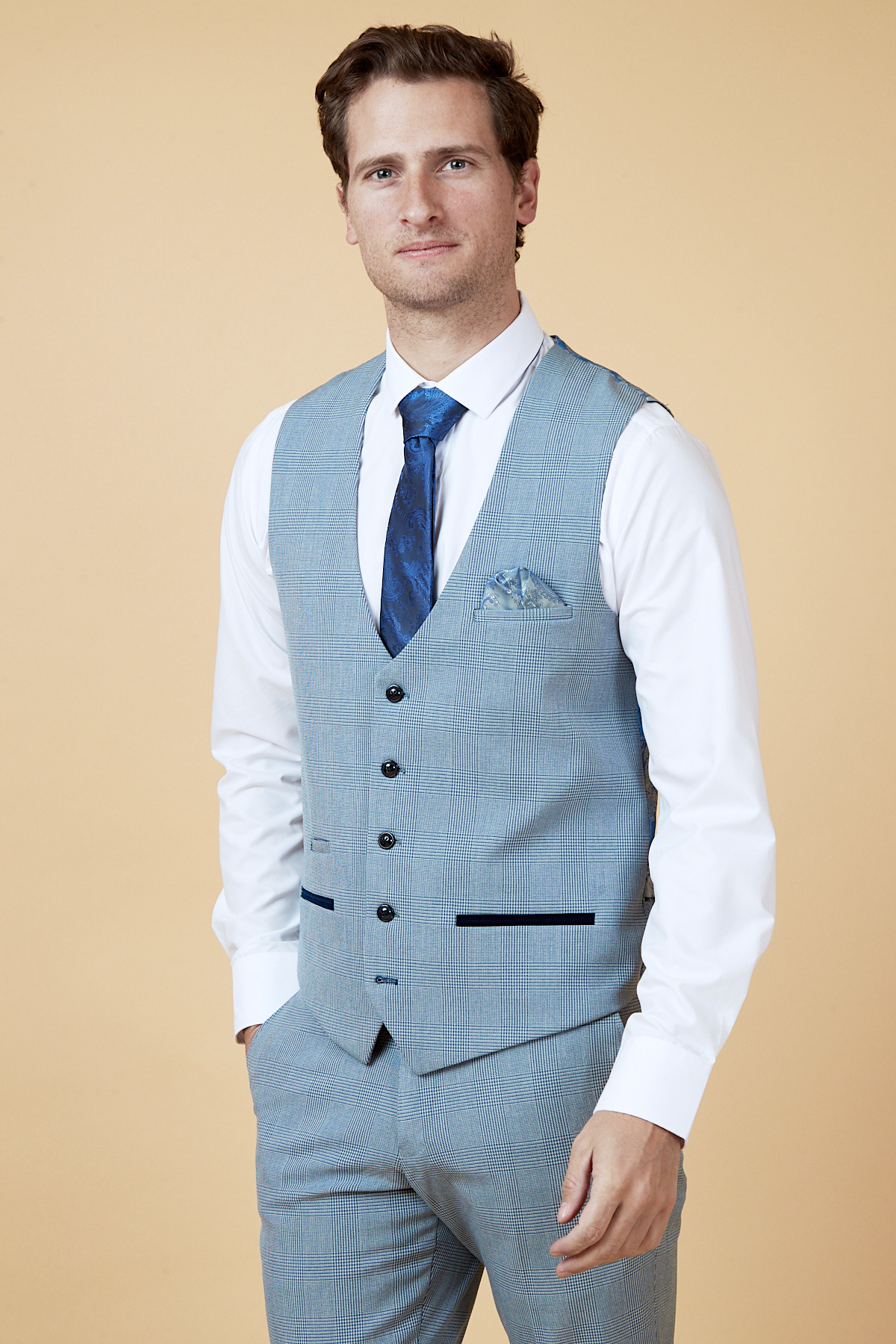 Everton midfielder James Garner wears the marcdarcy Bromley Sky three-piece suit—slim fit with a light blue vest, matching trousers, white shirt, and blue tie—standing against a beige background with short brown hair and a neutral expression.