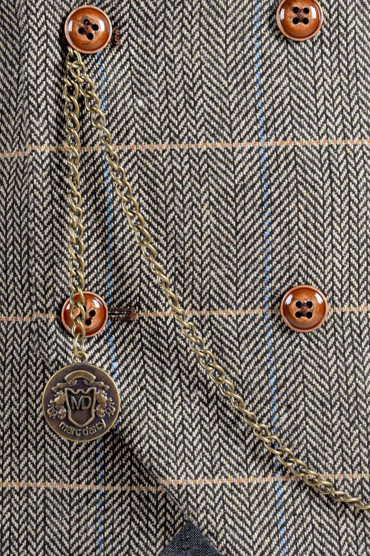 Close-up of a tweed jacket with herringbone pattern, brown buttons, and an Antique Style Gold Plated Marc Darcy T-Bar Waistcoat Chain, which includes an MD Velvet Keepsafe Pouch.