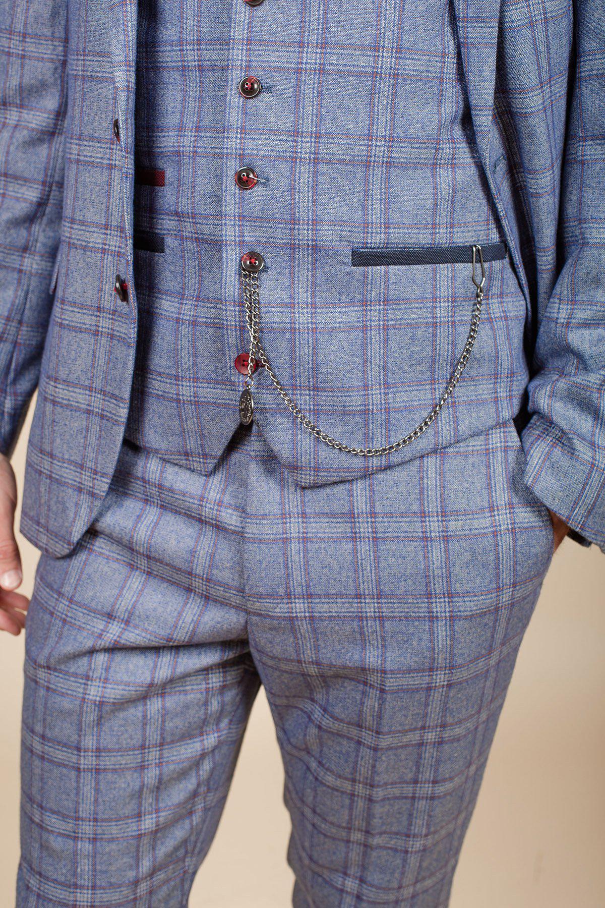 A person wears a tailored blue and gray plaid suit with a matching vest, accented by dark buttons and a Marc Darcy Antique Style Silver Plated T-Bar Waistcoat Chain, echoing Peaky Blinders style, hanging from the vest pocket.