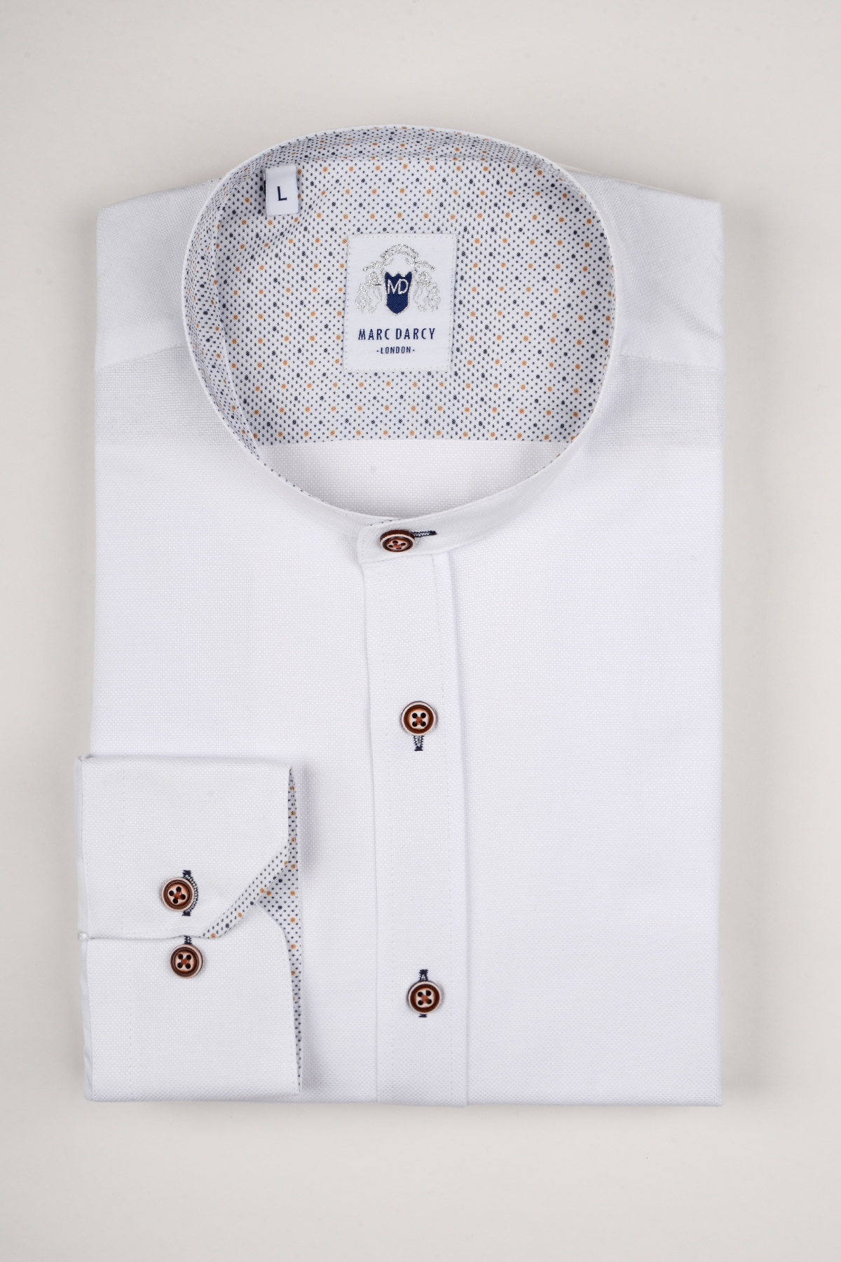 The ARCHIE White Grandad Collar Shirt by Marc Darcy features tan buttons, a patterned inner collar and cuff, and an oxford weave mandarin collar, displayed neatly folded on a plain light background.