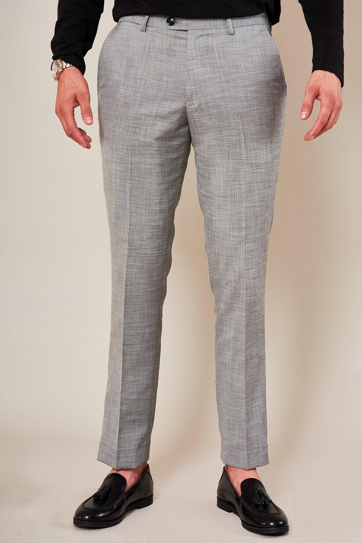 A person wearing marcdarcy's BEN - Silver Grey Slim Tailored Trousers, a black long-sleeve shirt, a silver watch, and black loafers stands against a plain, light-colored background. The person's head is not visible in the image.
