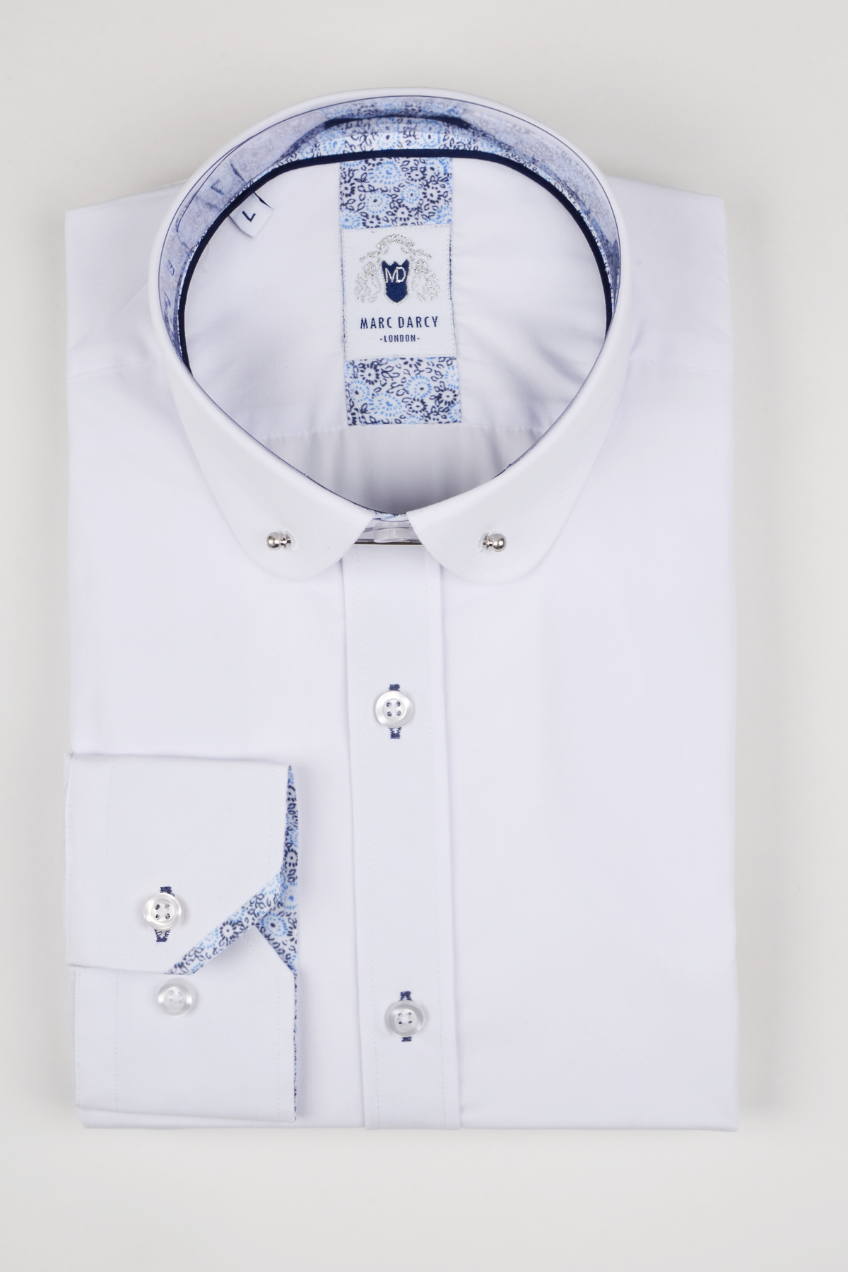 The BENSON White Penny Collar Shirt With Collar Bar by marcdarcy features a neatly folded design, silver collar bar, and blue patterned inner collar and cuffs, displayed on a plain light background.