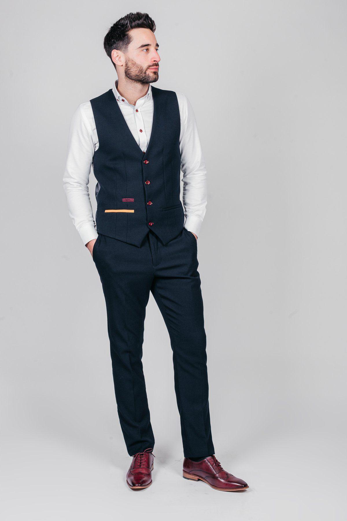 Newcastle United and England goalkeeper Nick Pope wears a marcdarcy JD4 navy suit: white shirt, navy vest with red buttons and paisley lining, matching trousers, and brown dress shoes, standing against a light gray background.