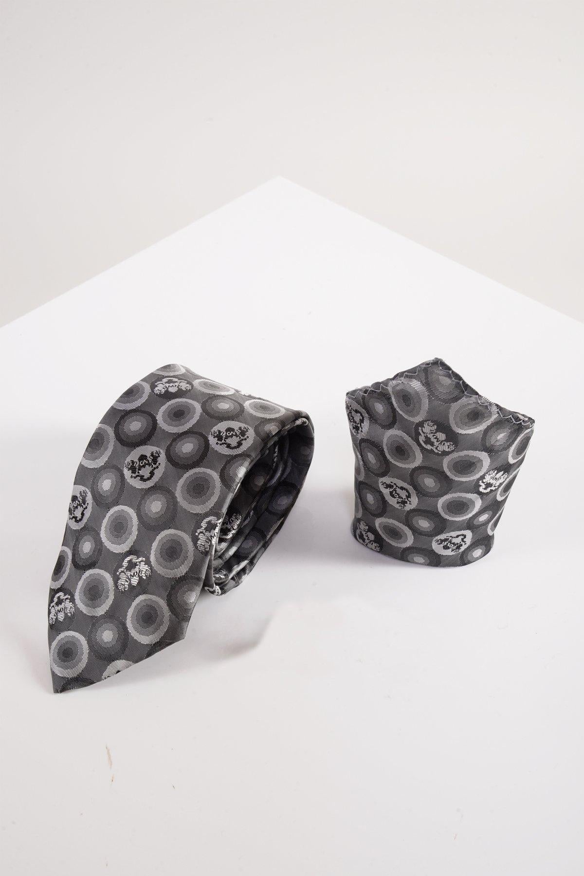 The Marc Darcy BUBBLES Grey Bubble Circle Print Tie and Pocket Square Set is shown on a white geometric surface, ideal for formalwear.