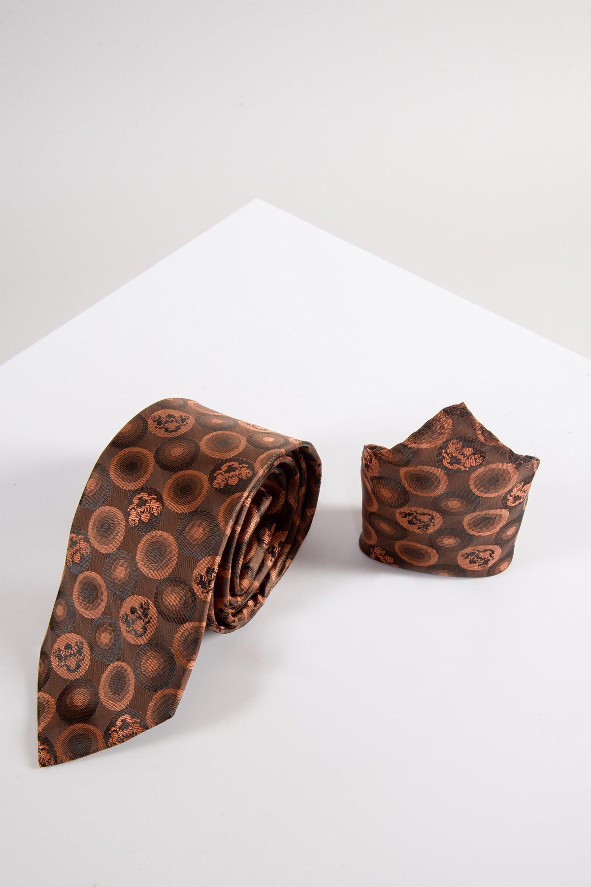 The BUBBLES Orange Brown Bubble Circle Print Tie and Pocket Square Set by Marc Darcy features circular patterns in rich tones, showcased on a white geometric surface against a light background—a refined accessory set.