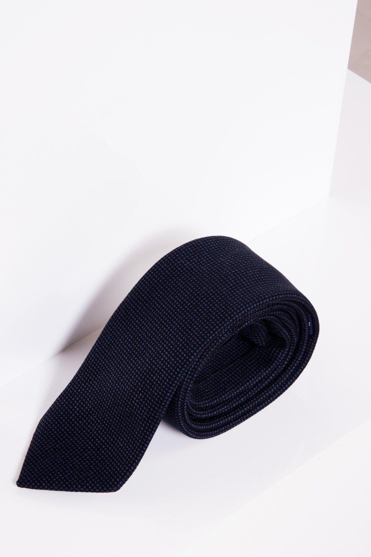The CALLUM Navy Birdseye Tie by Accessory, showcasing a subtle dotted pattern and refined birdseye weave, is neatly rolled up on a white surface against a clean white background.