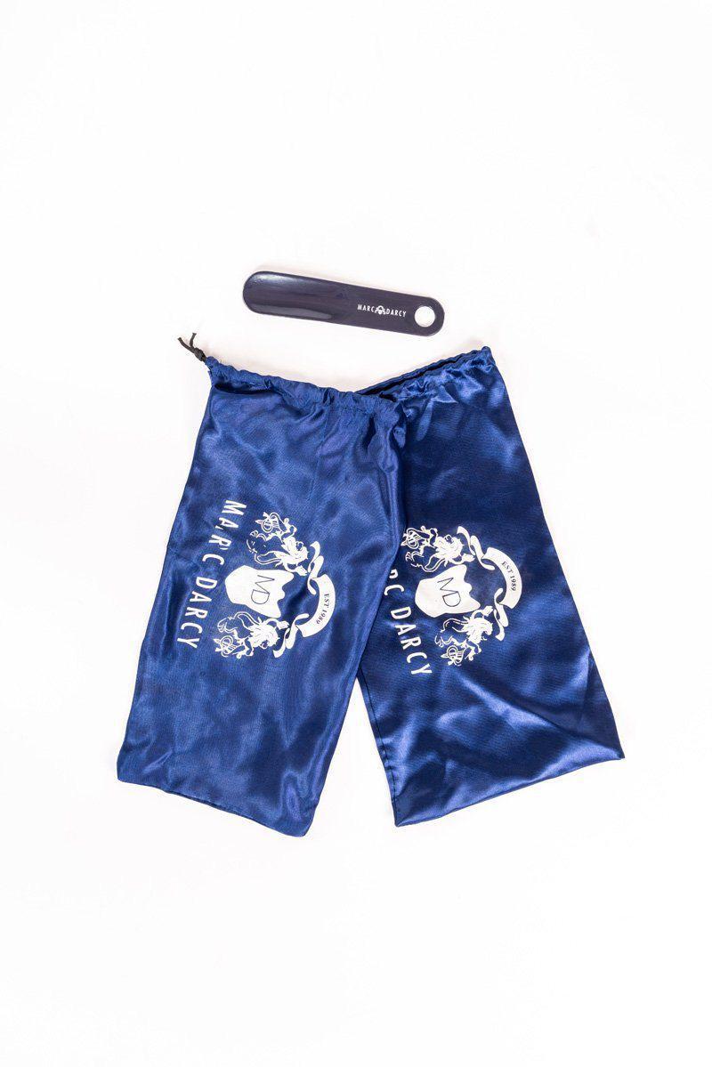 A navy blue satin drawstring pouch with a white Marc Darcy logo sits beside a black plastic Marc Darcy shoehorn—perfect accessories for your CARSON Mid Tan Wingtip Oxford Brogue Shoes—displayed on a crisp white background.