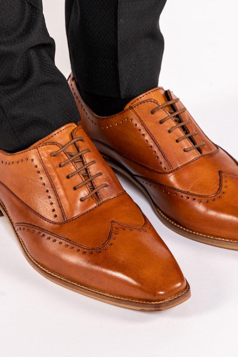 Close-up of the Marc Darcy CARSON Mid Tan Wingtip Oxford Brogue Shoe, crafted from full grain leather with brogue detailing, shown worn with black dress pants on a white background.