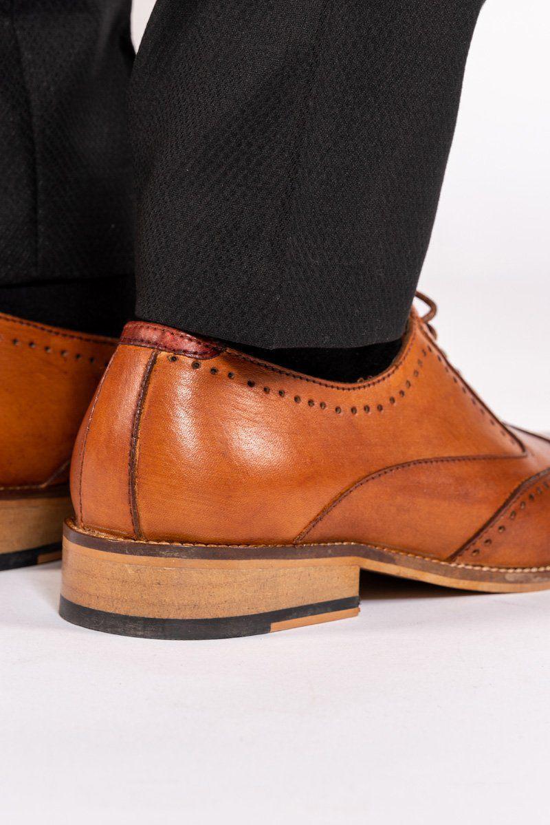 Close up of Marc Darcy’s CARSON - Mid Tan Wingtip Oxford Brogue Shoe in full grain leather, styled with black pants on a white background.