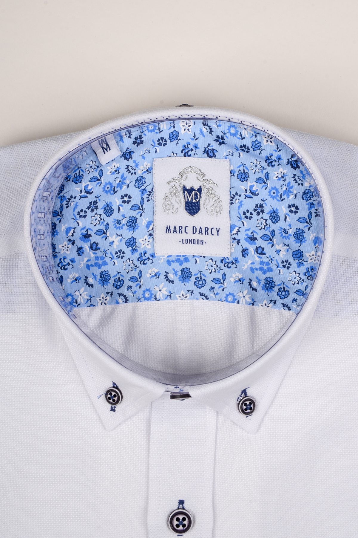 Close-up of the CHARLIE white Oxford shirt by Marc Darcy, featuring blue buttons, a smart casual style, and a visible label.