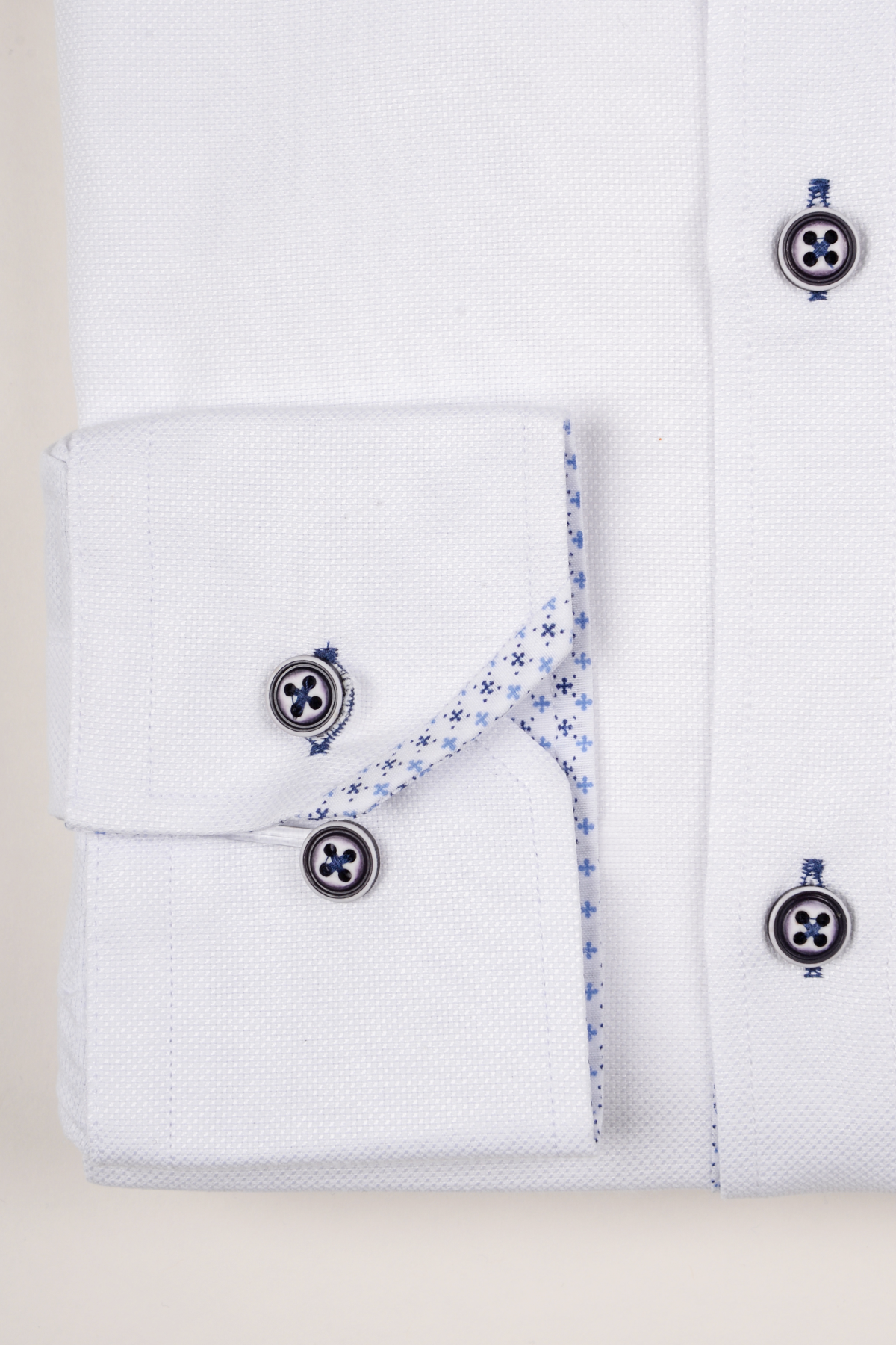 The CHARLIE White Oxford Shirt by Marc Darcy features blue buttons, a folded cuff with blue patterned lining, and is crafted from a cotton blend for a smart-casual look.