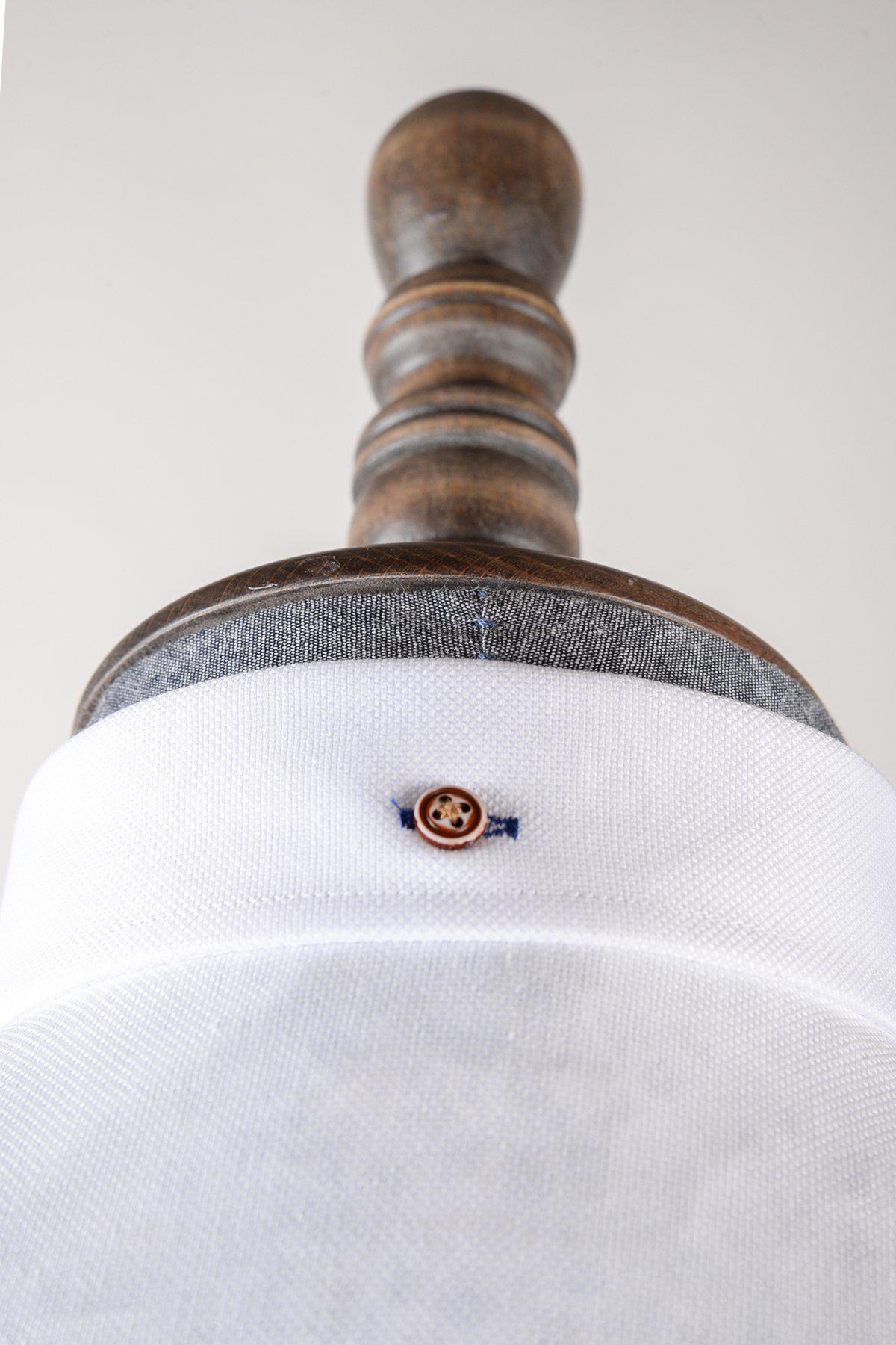 Close-up of the Marc Darcy CHARLIE white Oxford shirt on a mannequin, showcasing a single tan contrast button with blue stitching.