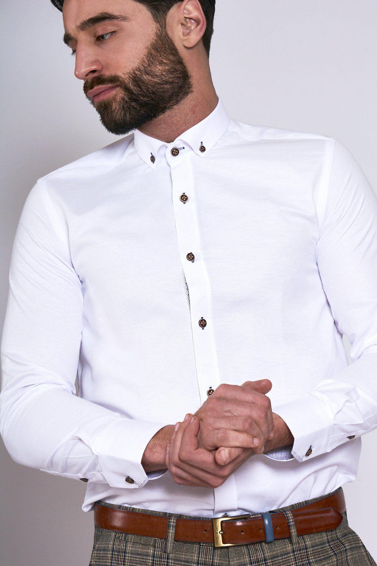 A bearded man wears the Marc Darcy CHARLIE white Oxford shirt with tan buttons, styled smart casually and paired with a brown belt over plaid pants.
