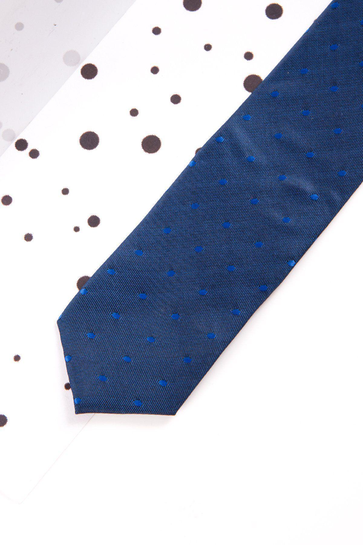 The Marc Darcy Childrens Blue Polka Dot Print Tie, a pre-tied accessory with an adjustable elasticated neck strap, is shown on a white surface with black dots, partially covered by a translucent sheet featuring similar dot patterns.