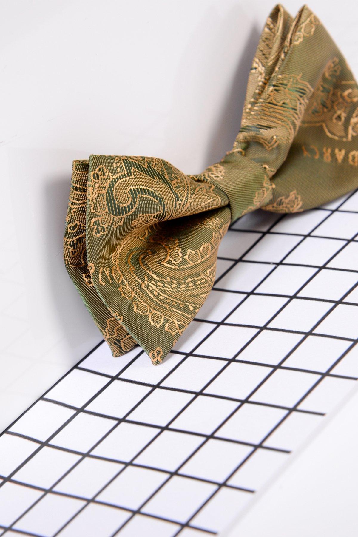 The Marc Darcy Childrens Gold Tan Paisley Print Bow Tie lies on a white surface with a black grid, showcasing intricate gold patterns and silky fabric—an ideal accessory for a childs formal look.