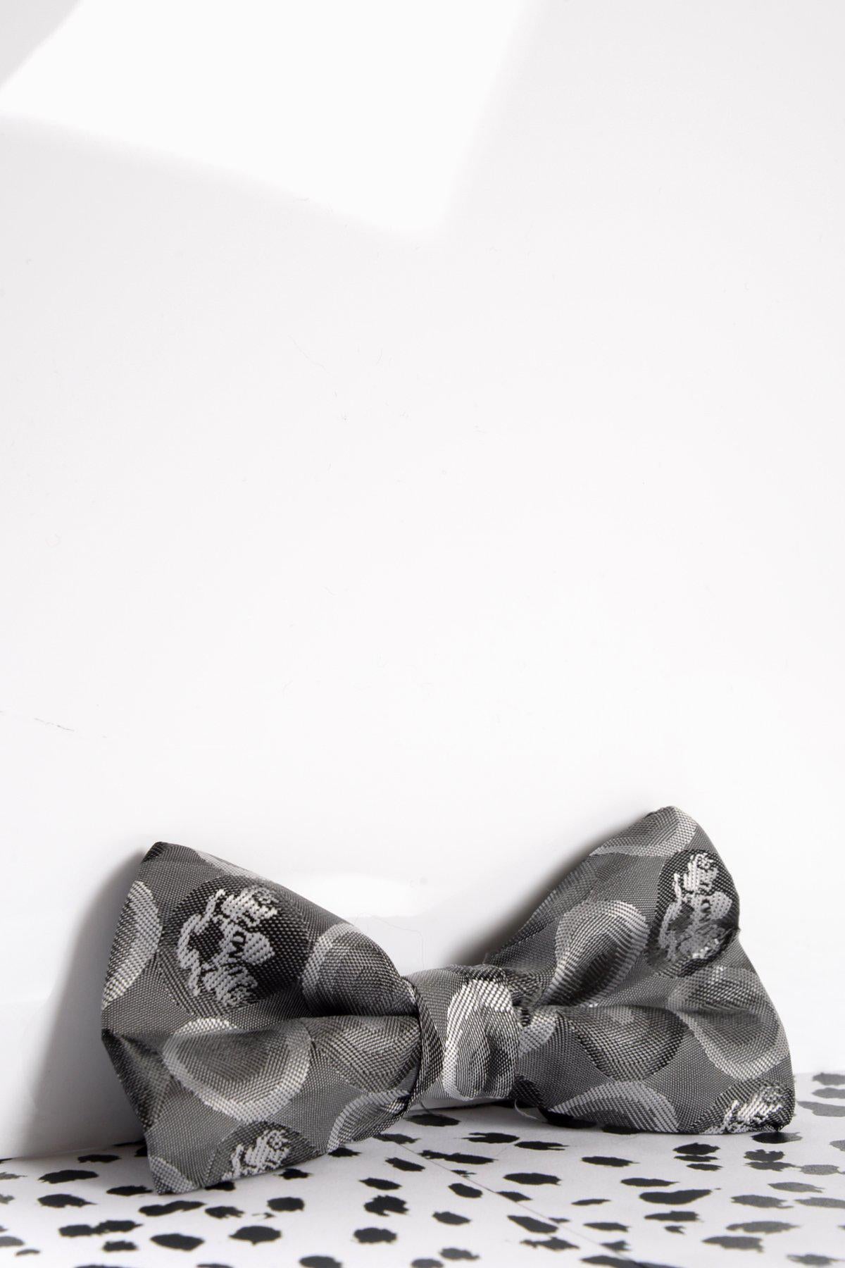 The Marc Darcy Children's Grey Bubble Circle Print Bow Tie sits on a white surface with black spots, set against a plain white background.