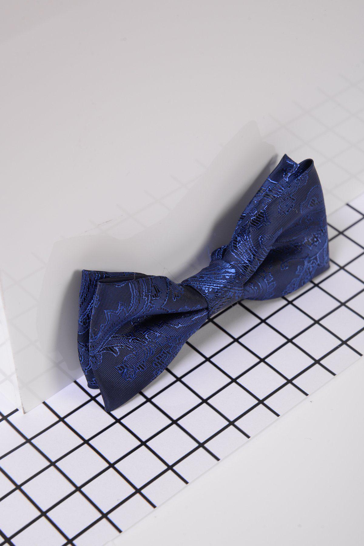 The Marc Darcy Childrens Navy Paisley Print Bow Tie with an adjustable neck strap sits on a white surface featuring a black grid pattern, partially covered by a semi-transparent sheet.