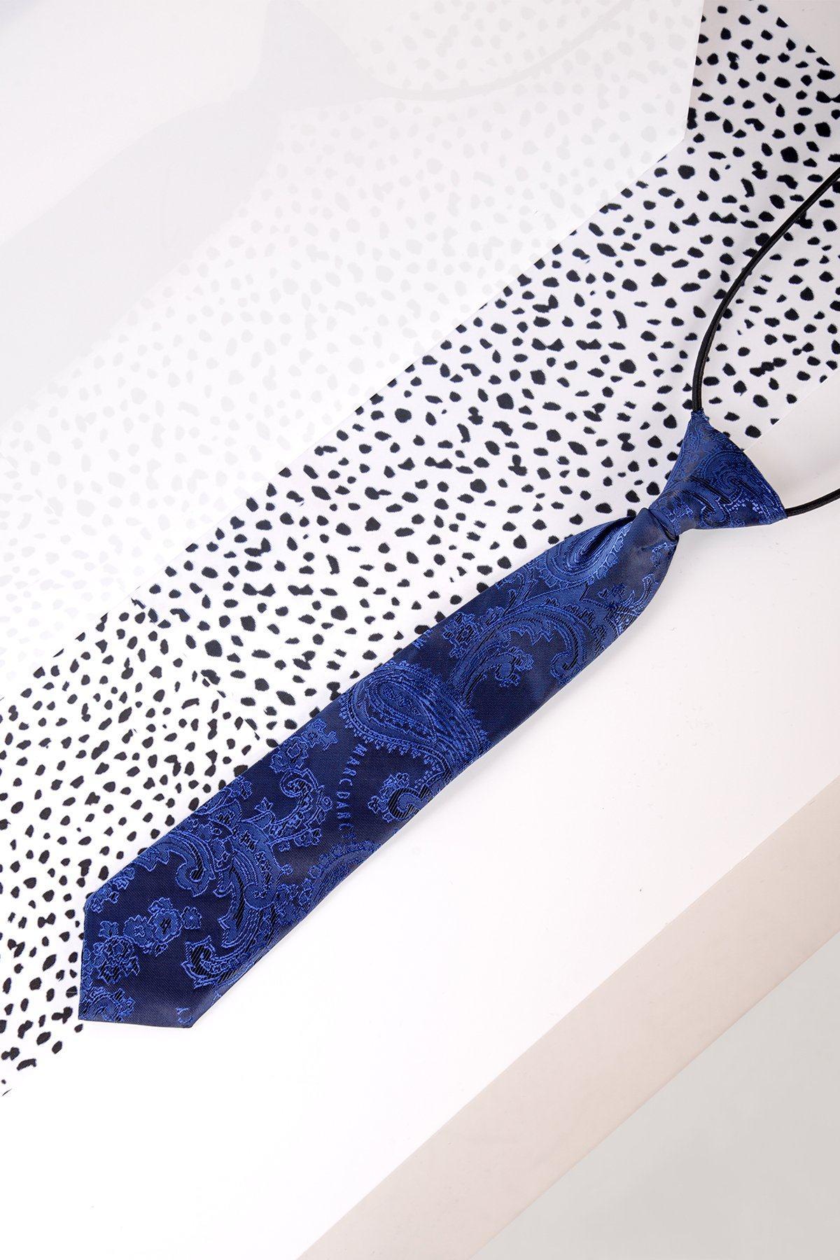 A Childrens Navy Paisley Print Tie by Marc Darcy with an elastic band is placed on a white surface with black polka dots.