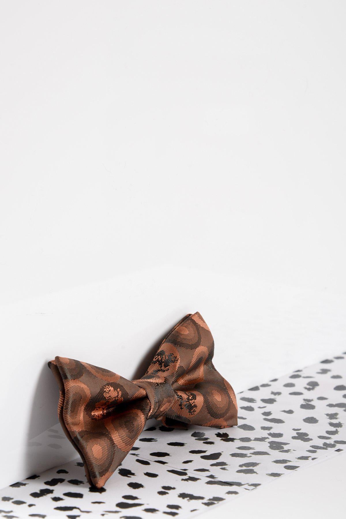 The Marc Darcy Childrens Orange Brown Bubble Circle Print Bow Tie, featuring an adjustable neck strap, is displayed on a white surface with black irregular polka dots against a plain white background.