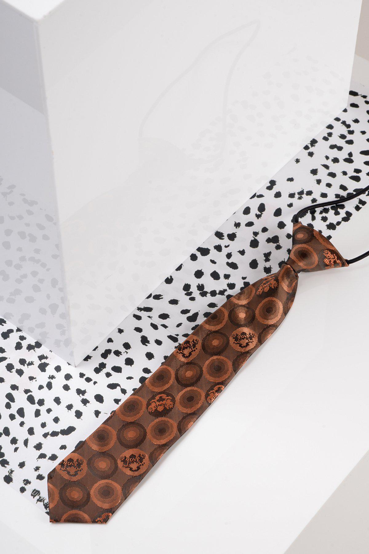 The Marc Darcy Childrens Orange Brown Bubble Circle Print Tie rests on a white surface with black speckles, beside a glossy white box reflecting part of the tie.