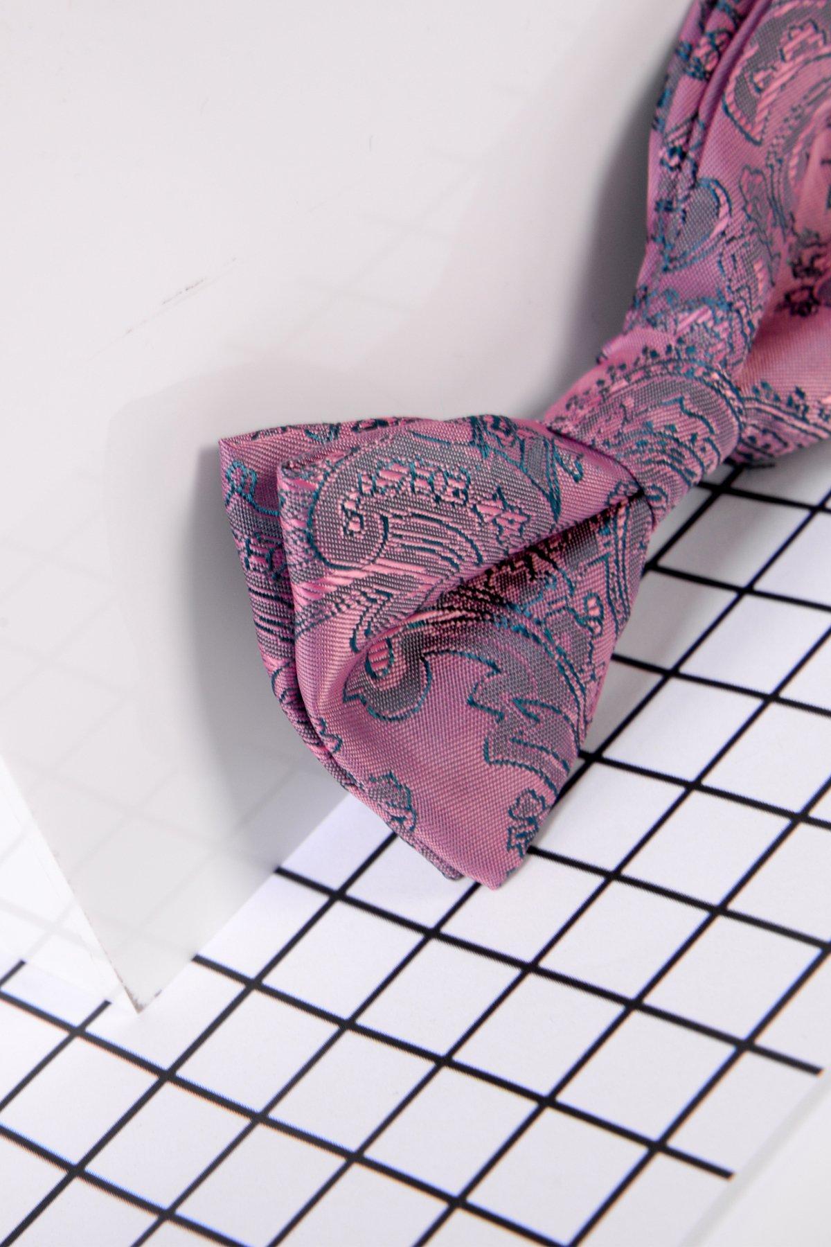 Close-up of the Marc Darcy Childrens Pink Paisley Print Bow Tie in pink and blue, resting on a white surface with a black grid—a cropped frame highlights this stylish accessory for formal childrens outfits.
