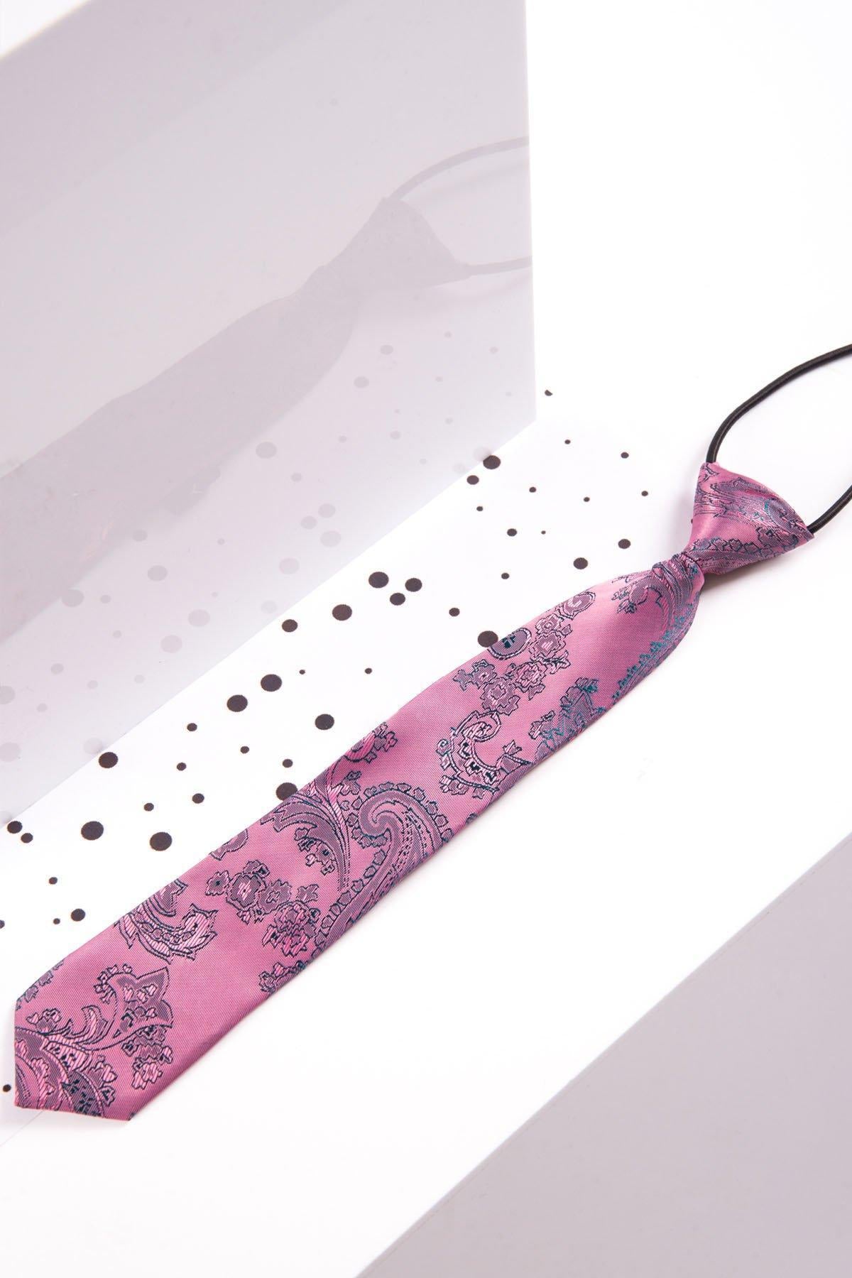 The Marc Darcy Children's Pink Paisley Print Tie is shown on a white background with black dots and a reflective surface—ideal for bringing flair to a boys' three-piece suit or the outfit of a fashionable page boy.