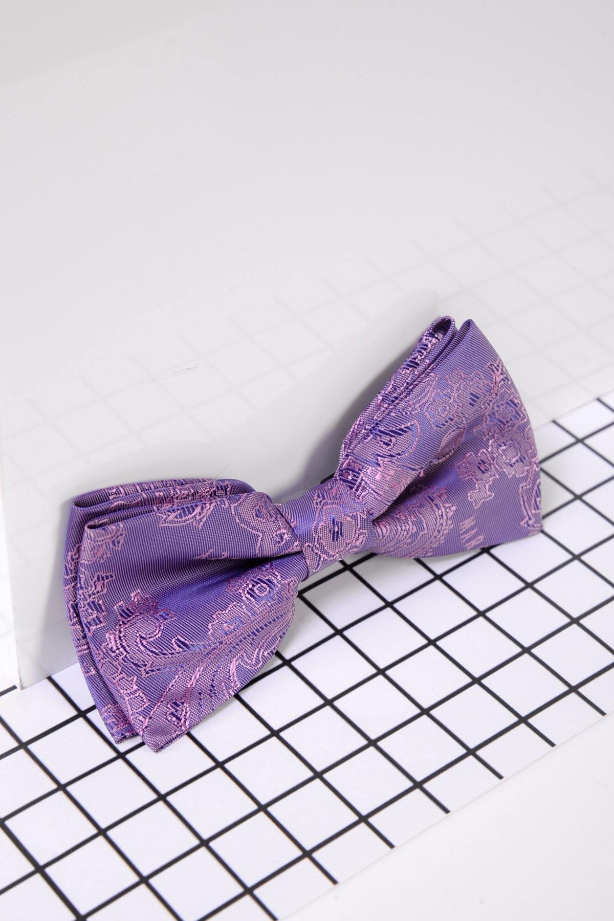 The Marc Darcy Childrens Purple Paisley Print Bow Tie, featuring an adjustable neck strap, is crafted from silky fabric and displayed on a white surface with a black grid design.